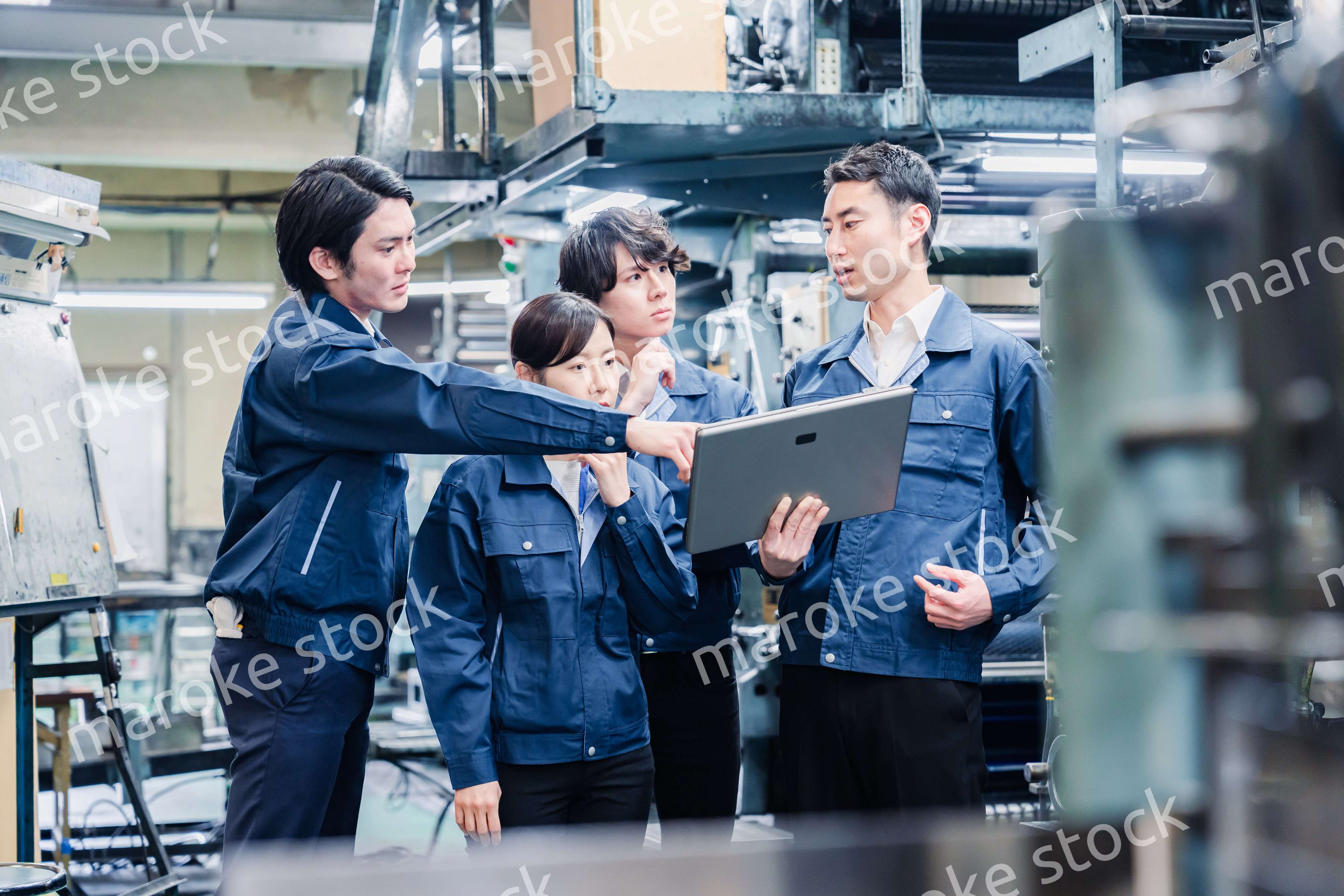 タブレット端末を見ながら会議をする工場スタッフ