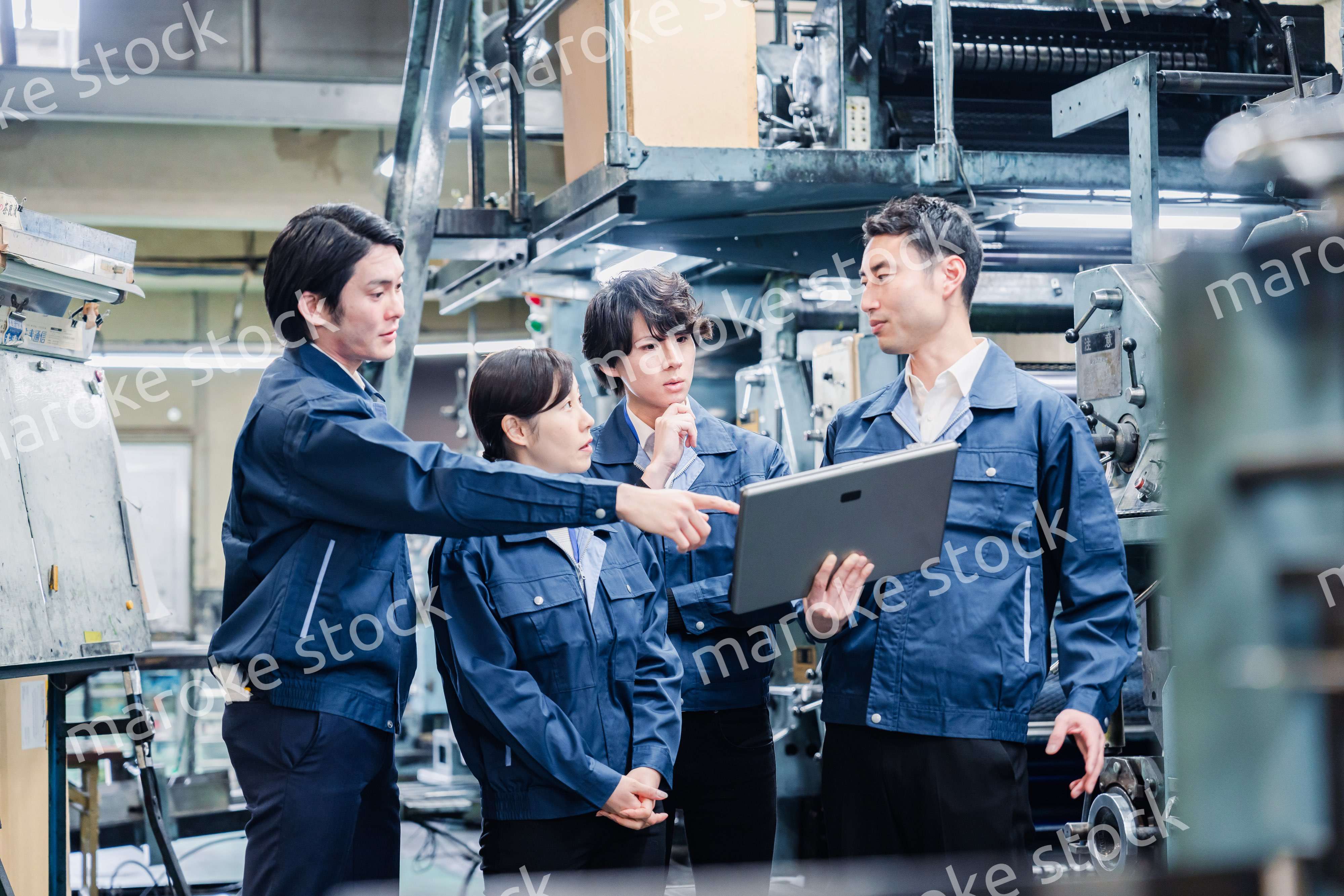 タブレット端末を見ながら会議をする工場スタッフ