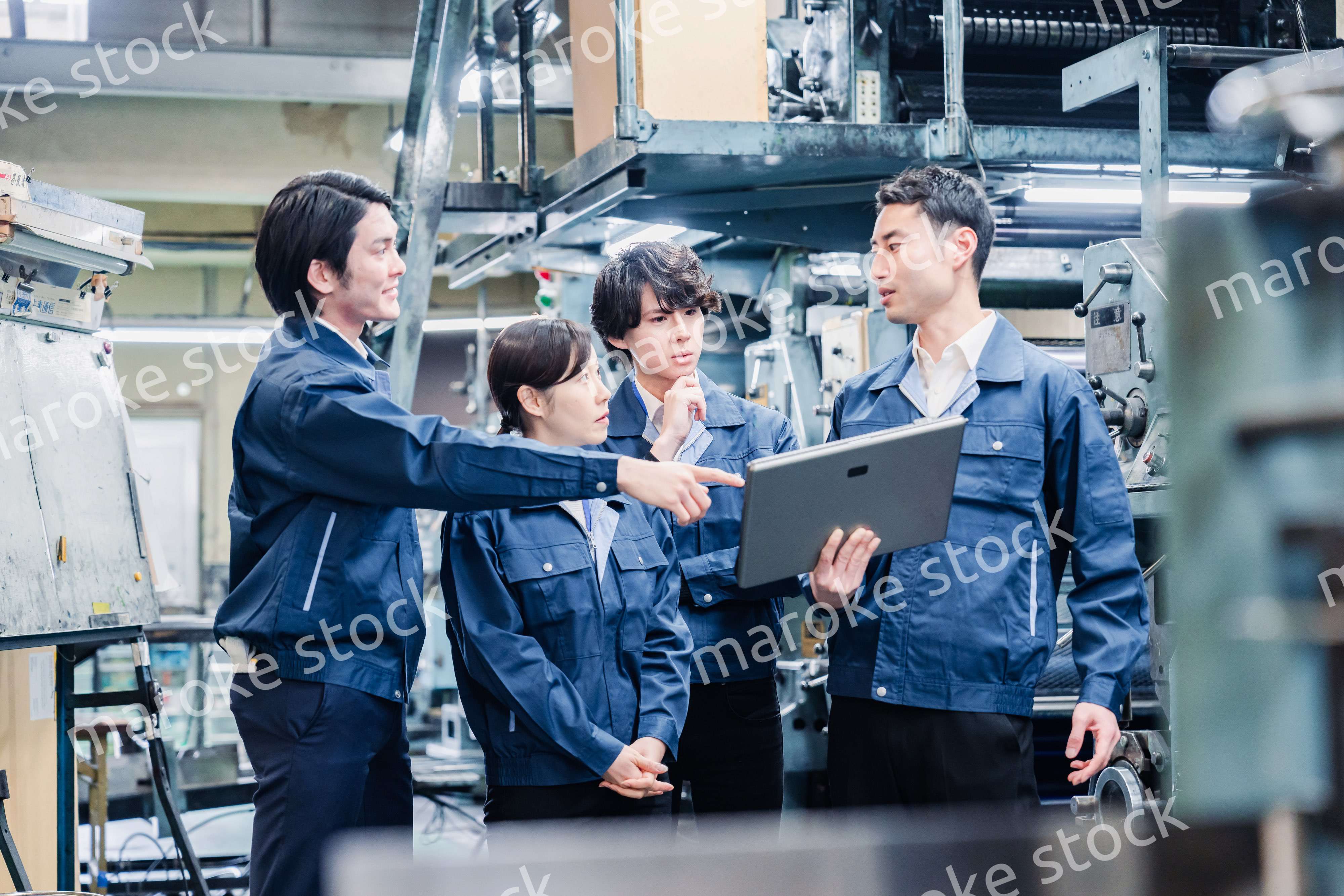 タブレット端末を見ながら会議をする工場スタッフ