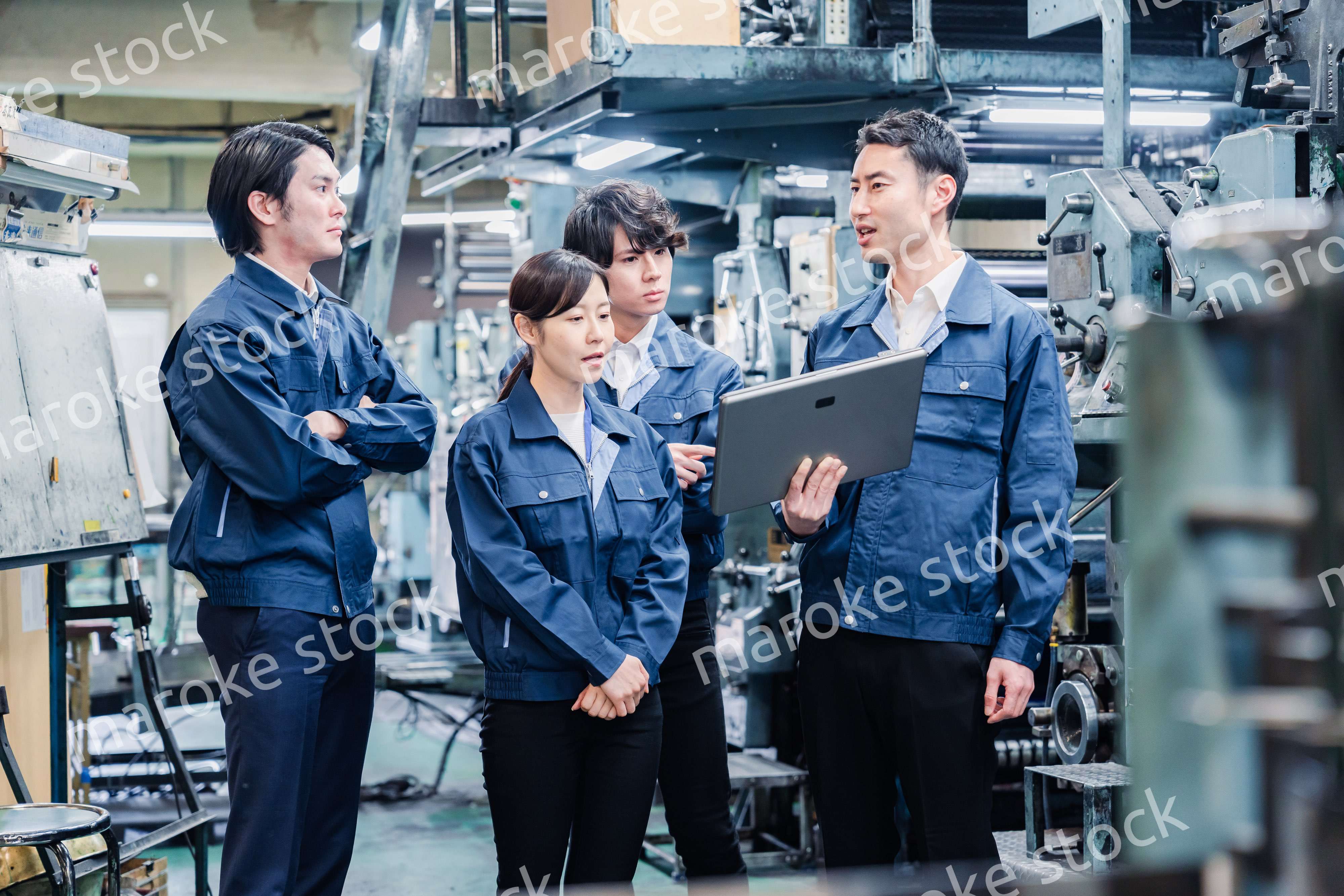 タブレット端末を見ながら会議をする工場スタッフ