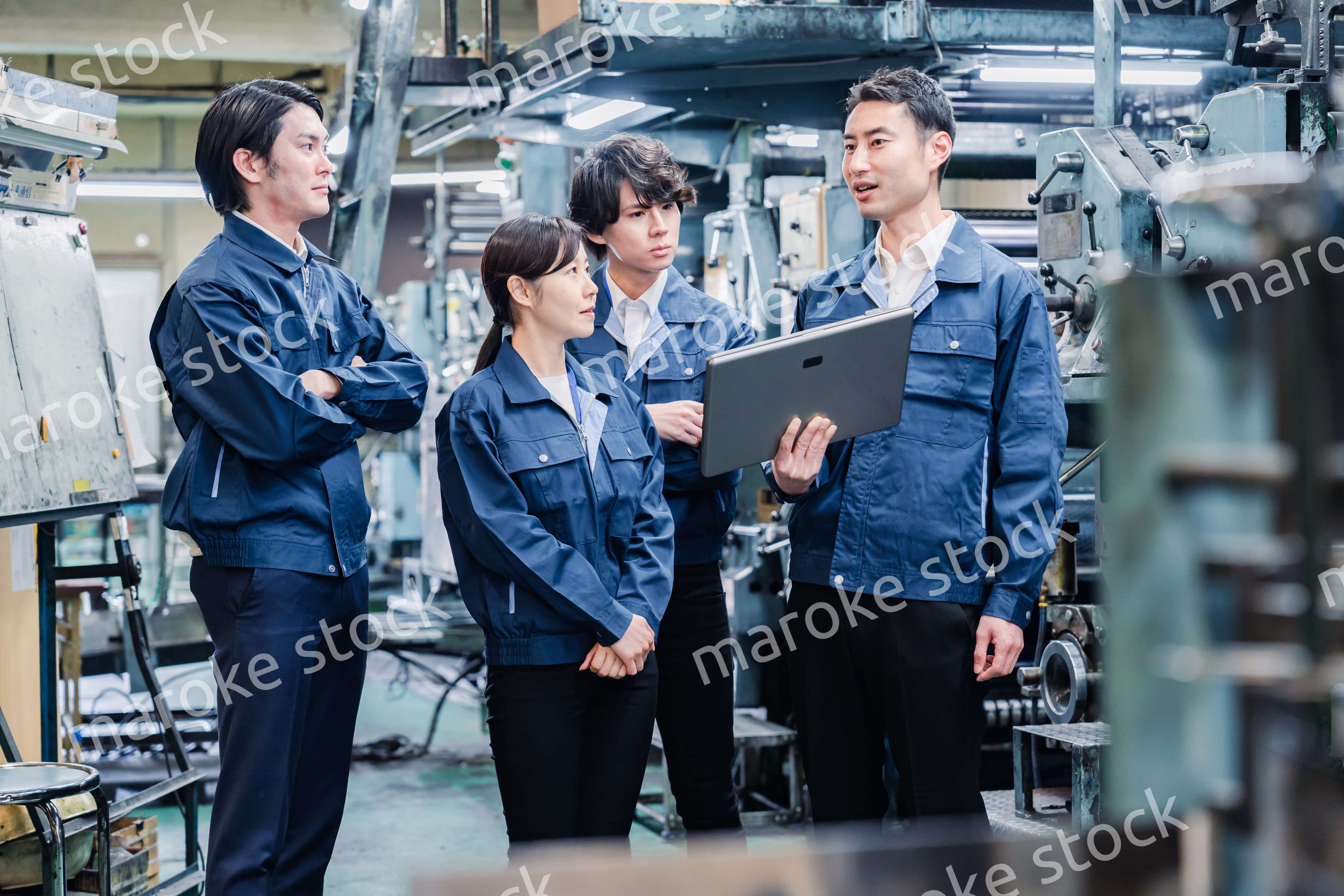 タブレット端末を見ながら会議をする工場スタッフ