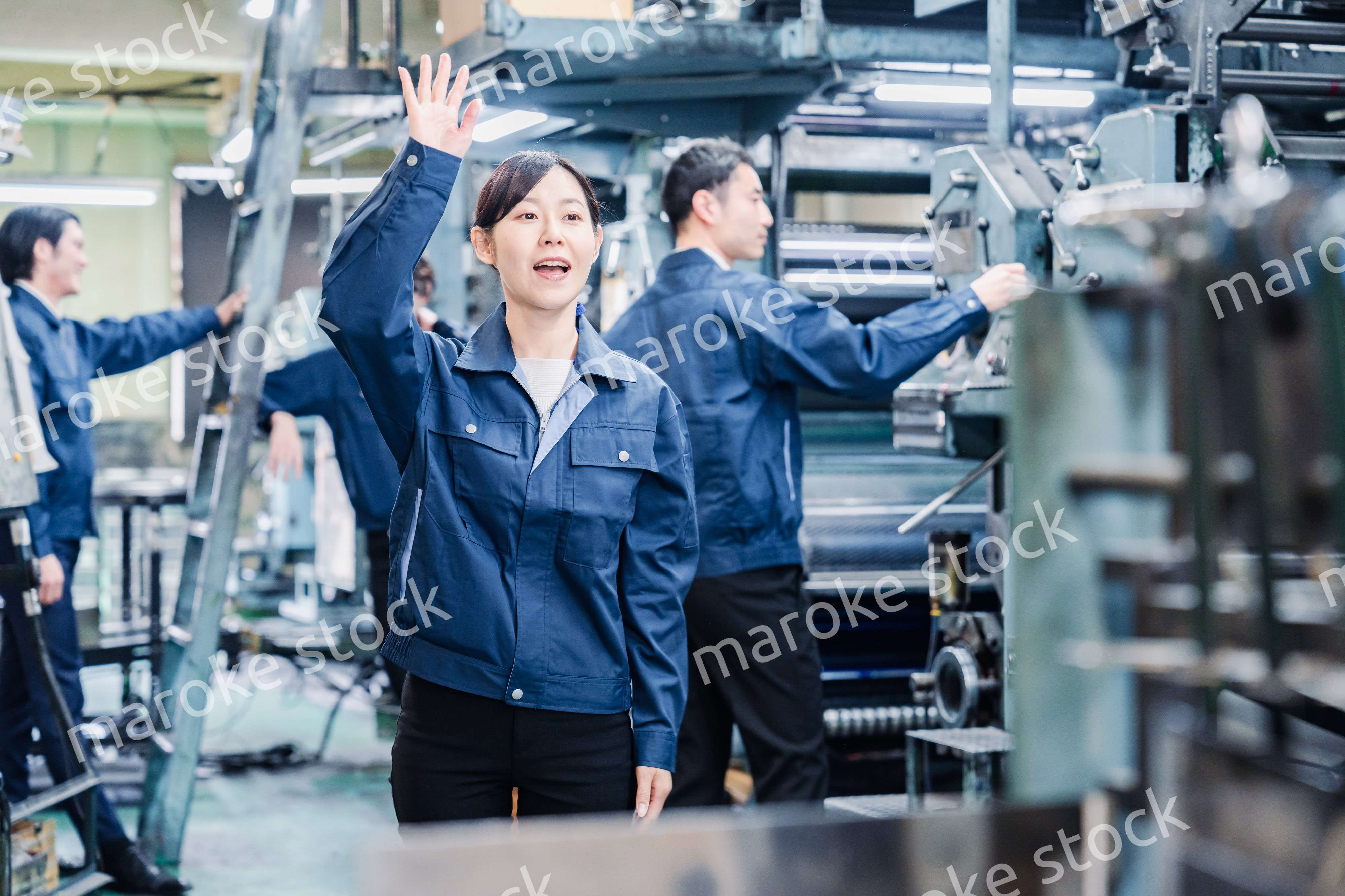 工場で手をふる女性の労働者