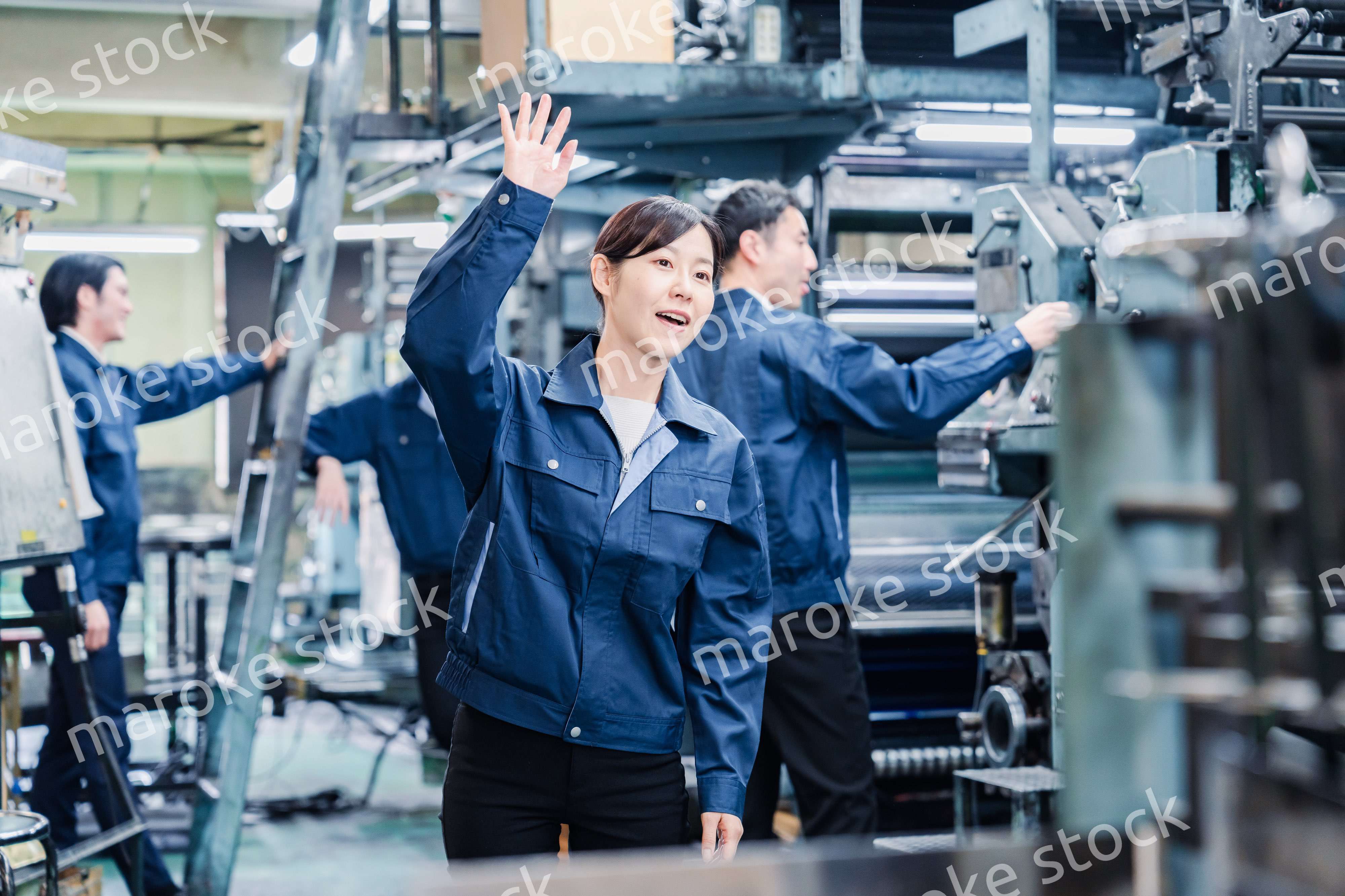 工場で手をふる女性の労働者