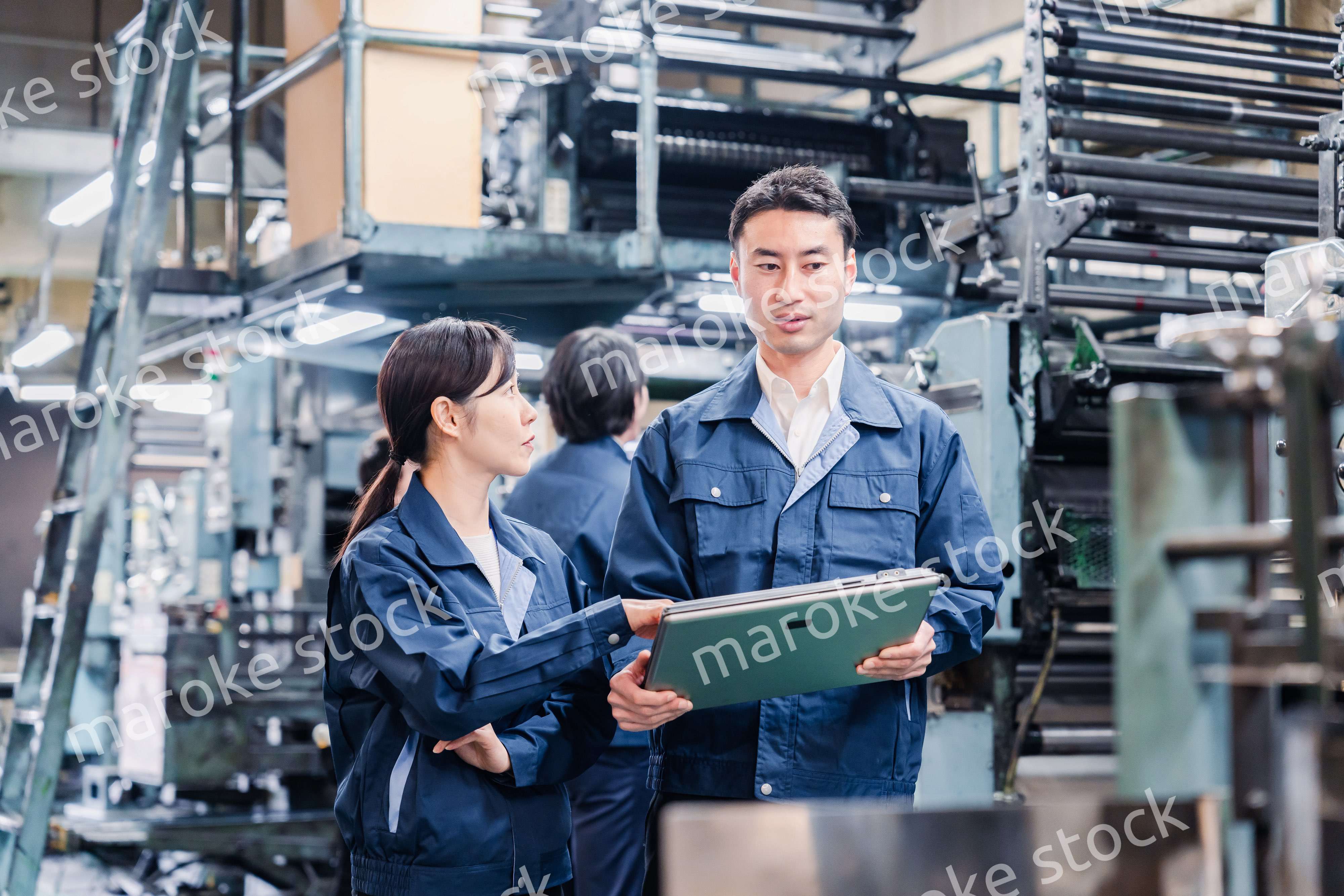 タブレットを見ながら工場で議論をするスタッフ