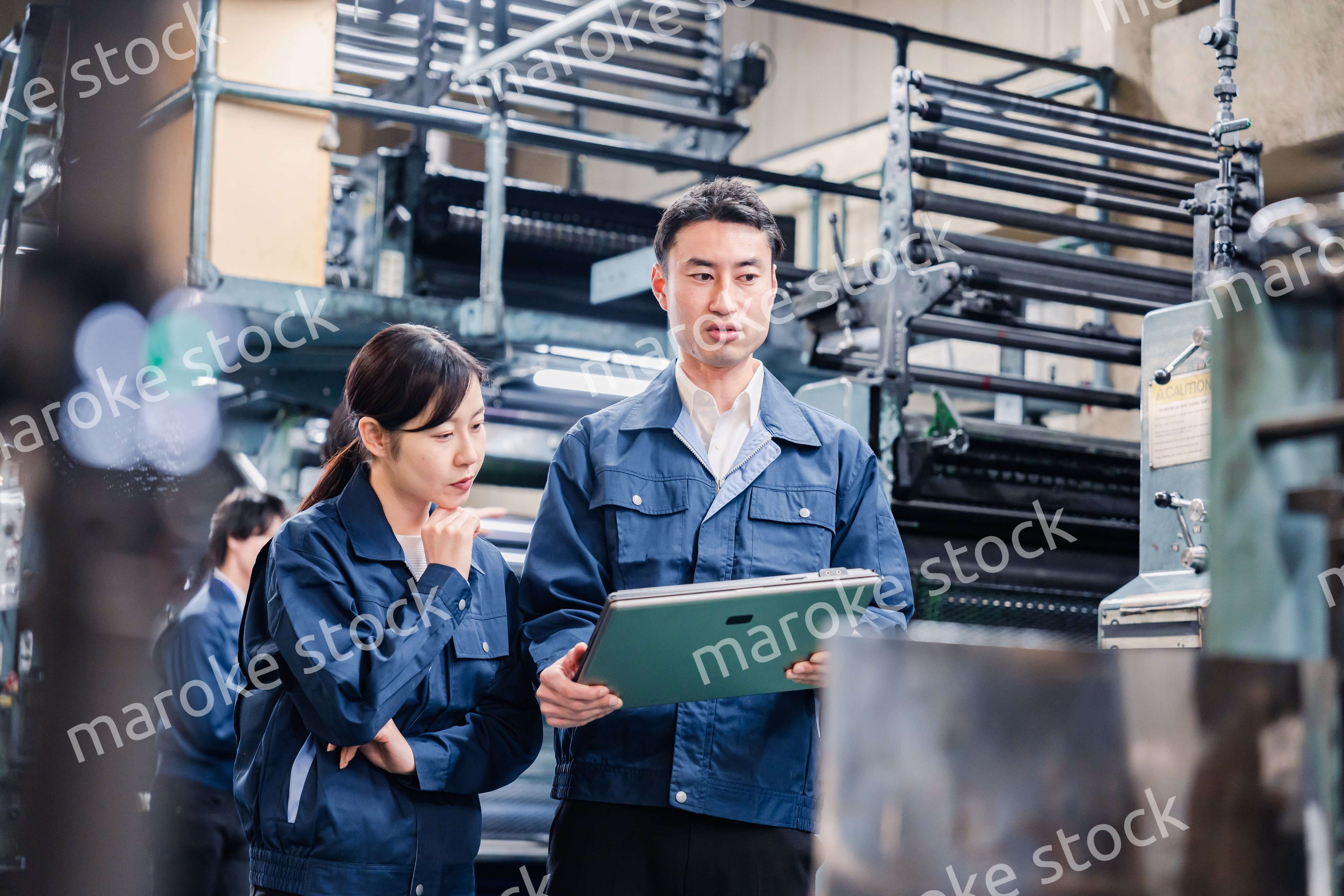 タブレットを見ながら工場で議論をするスタッフ