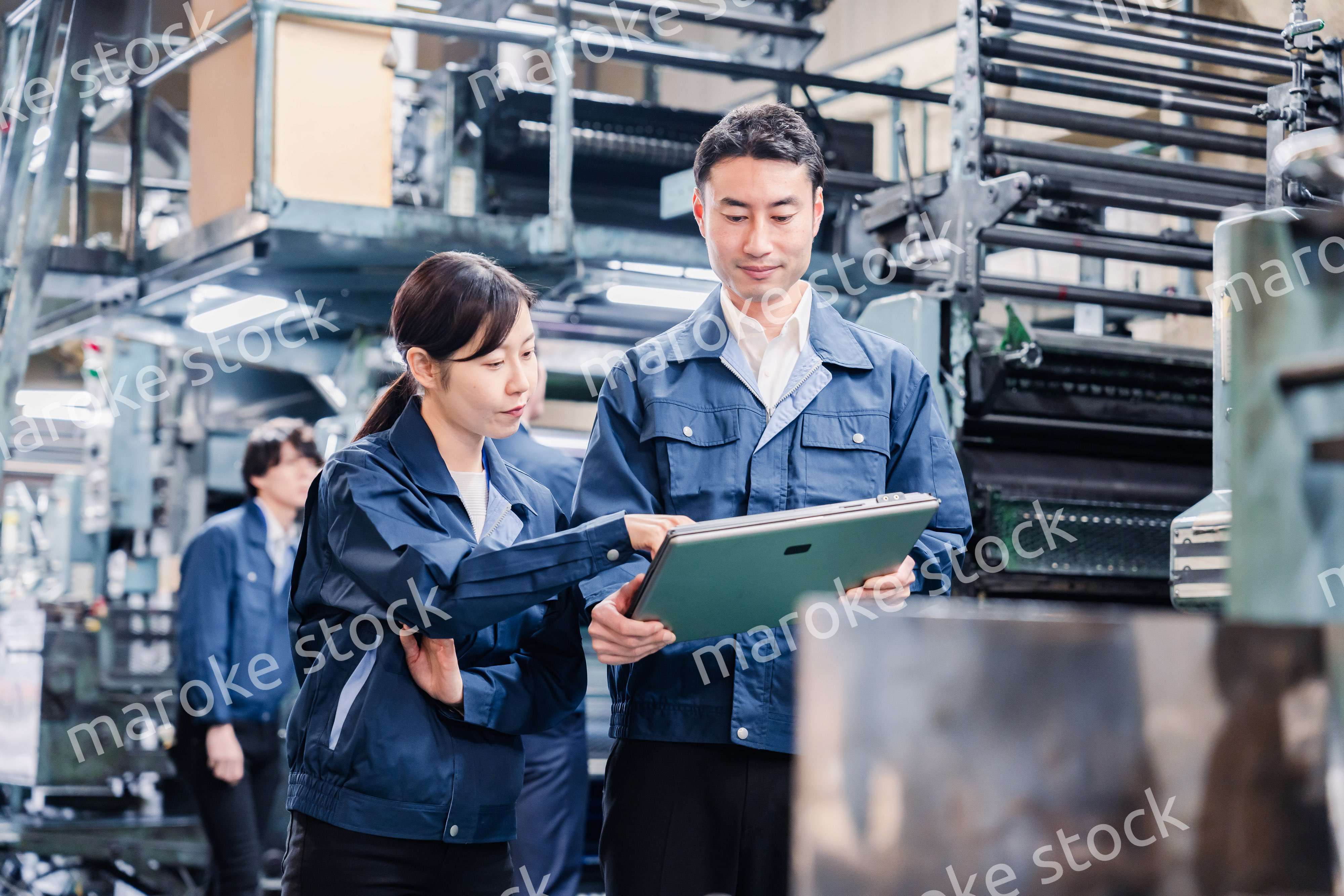 タブレットを見ながら工場で議論をするスタッフ