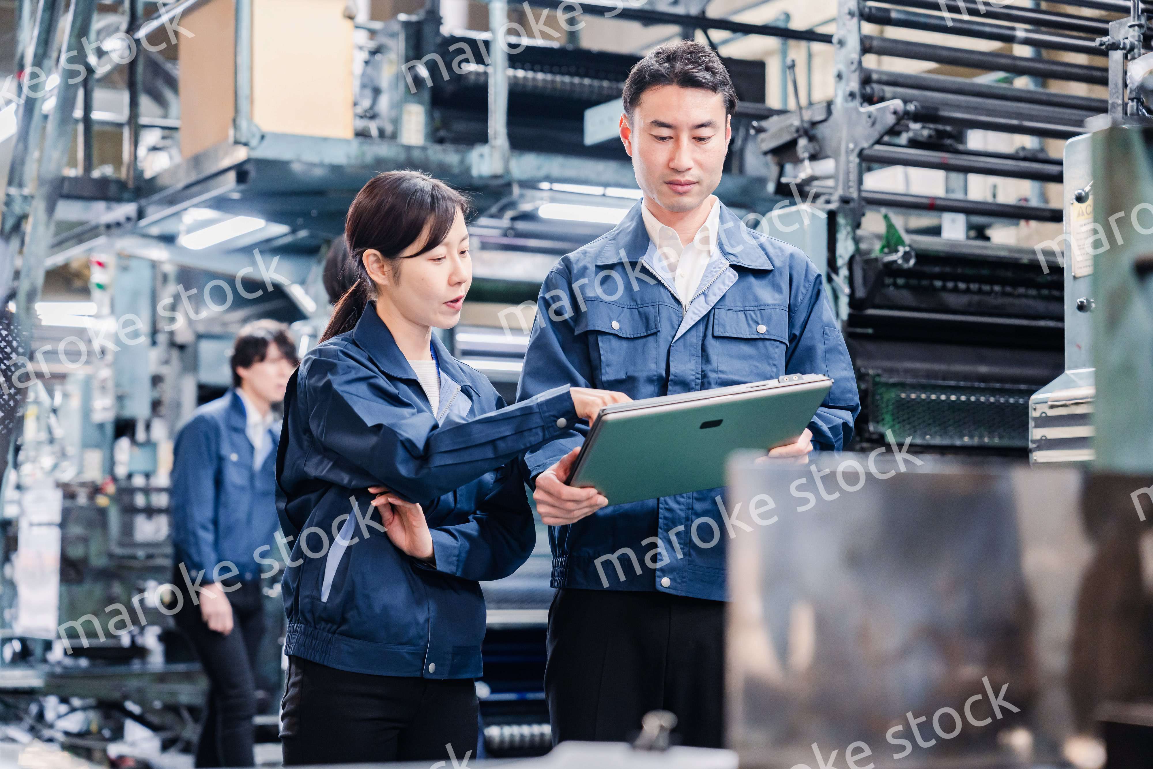 タブレットを見ながら工場で議論をするスタッフ