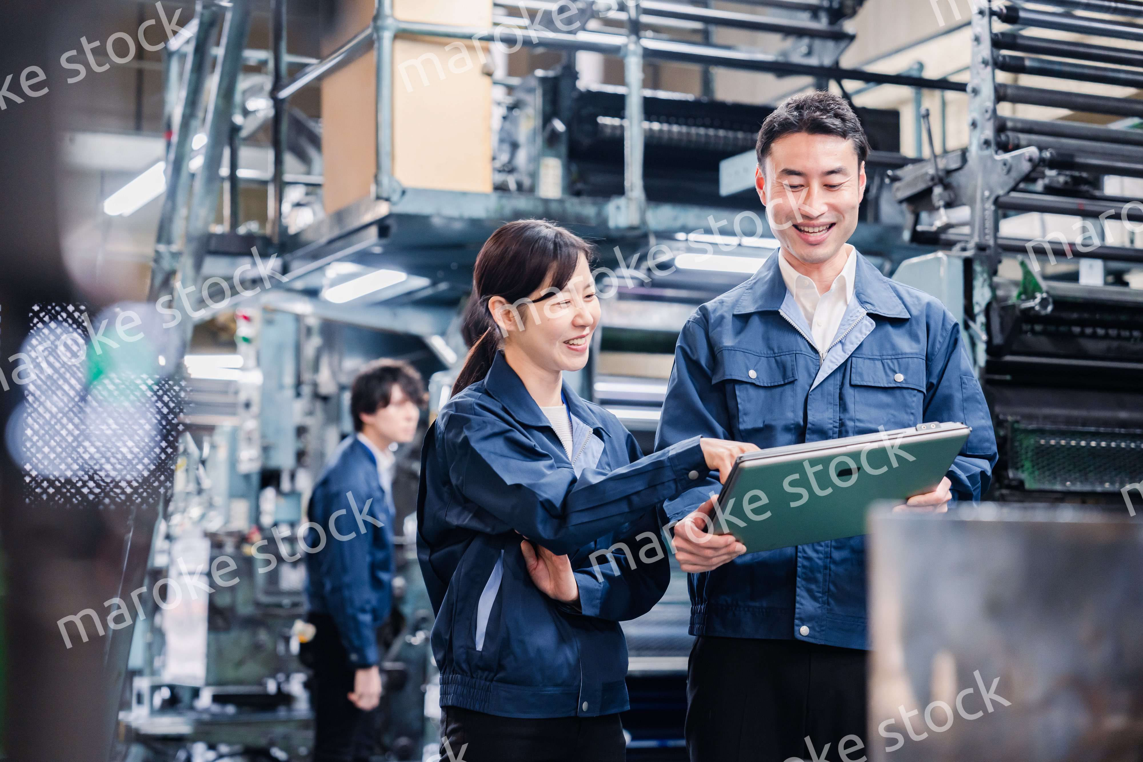タブレットを見ながら工場で議論をするスタッフ