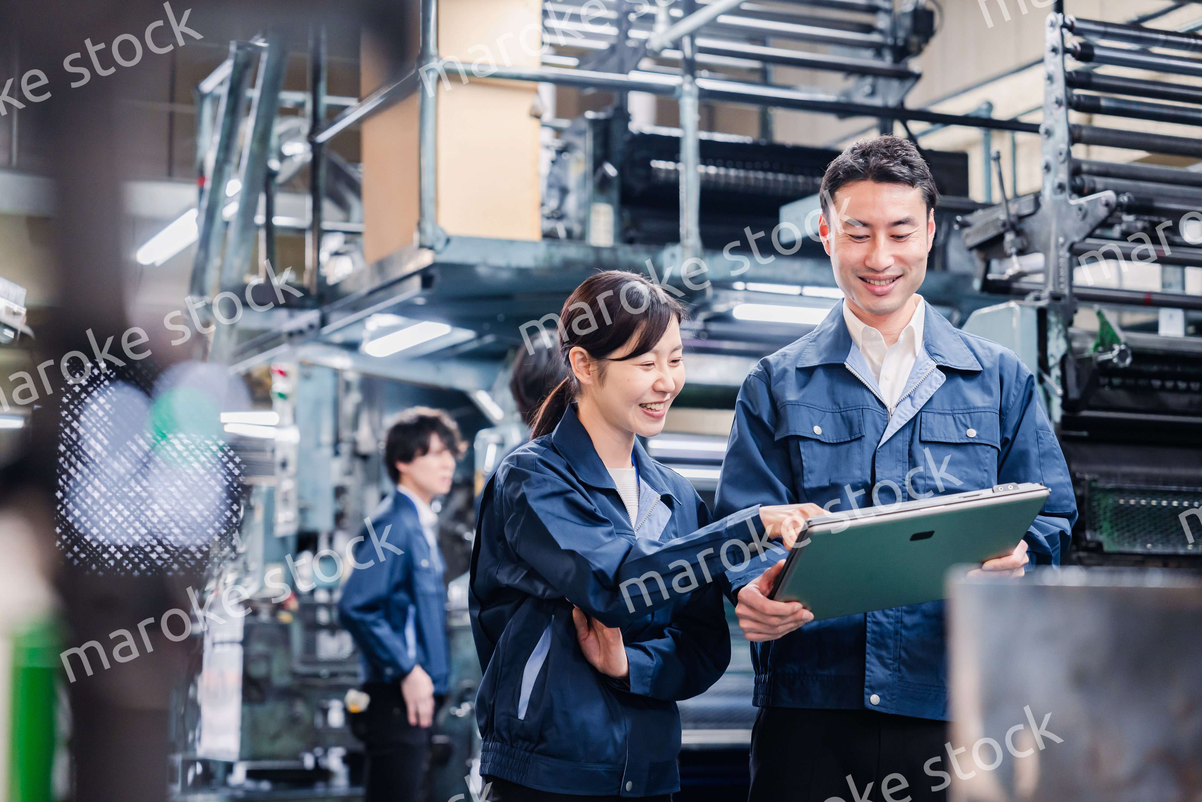 タブレットを見ながら工場で議論をするスタッフ