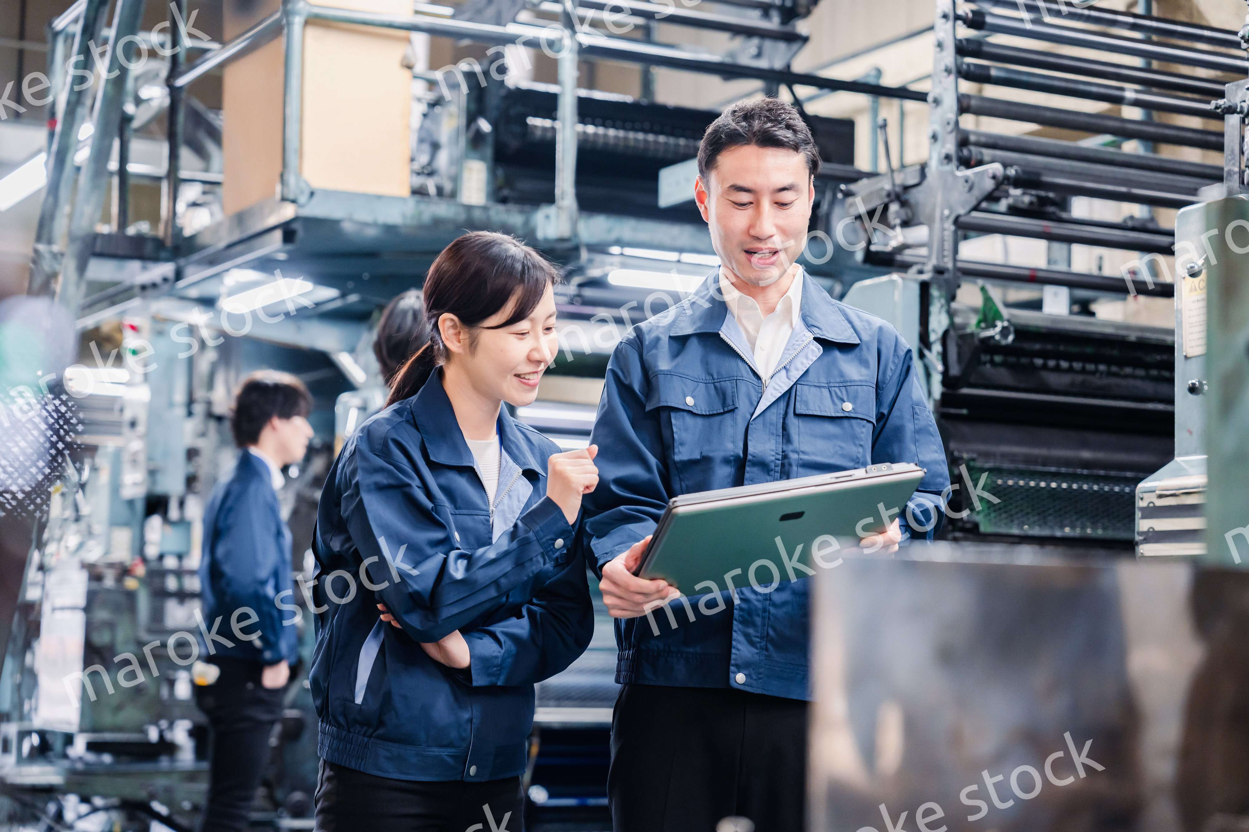 タブレットを見ながら工場で議論をするスタッフ