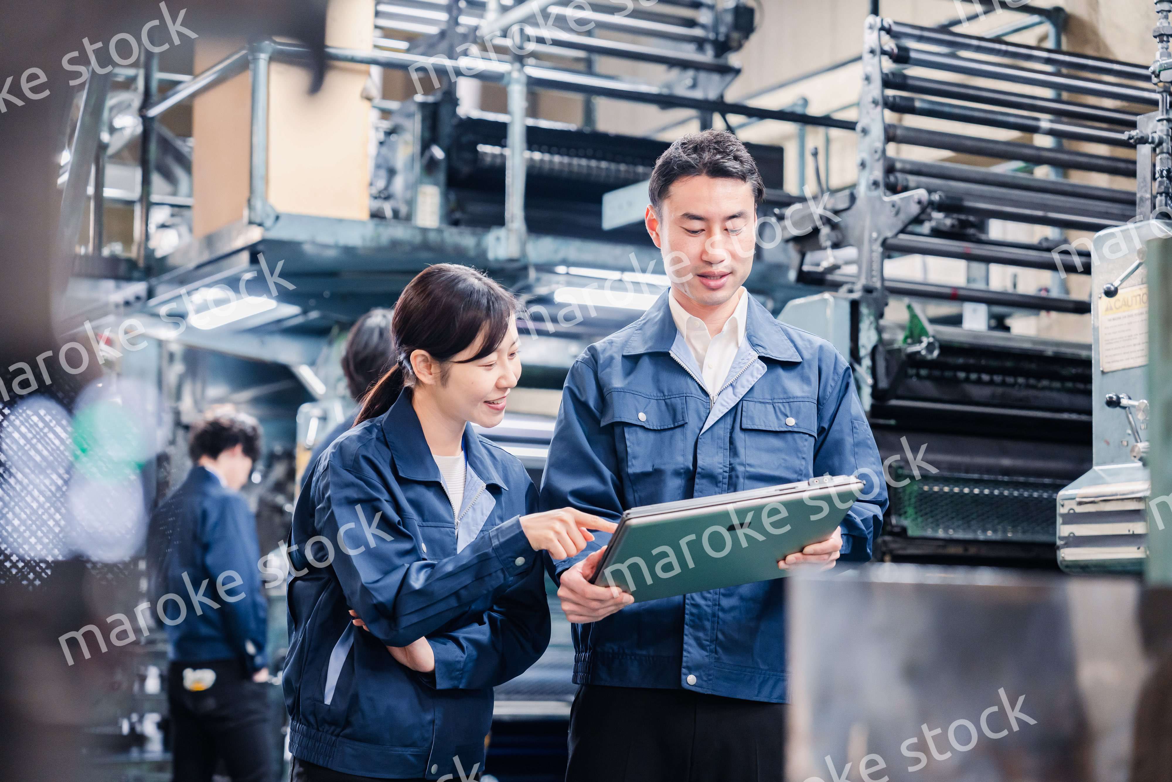 タブレットを見ながら工場で議論をするスタッフ