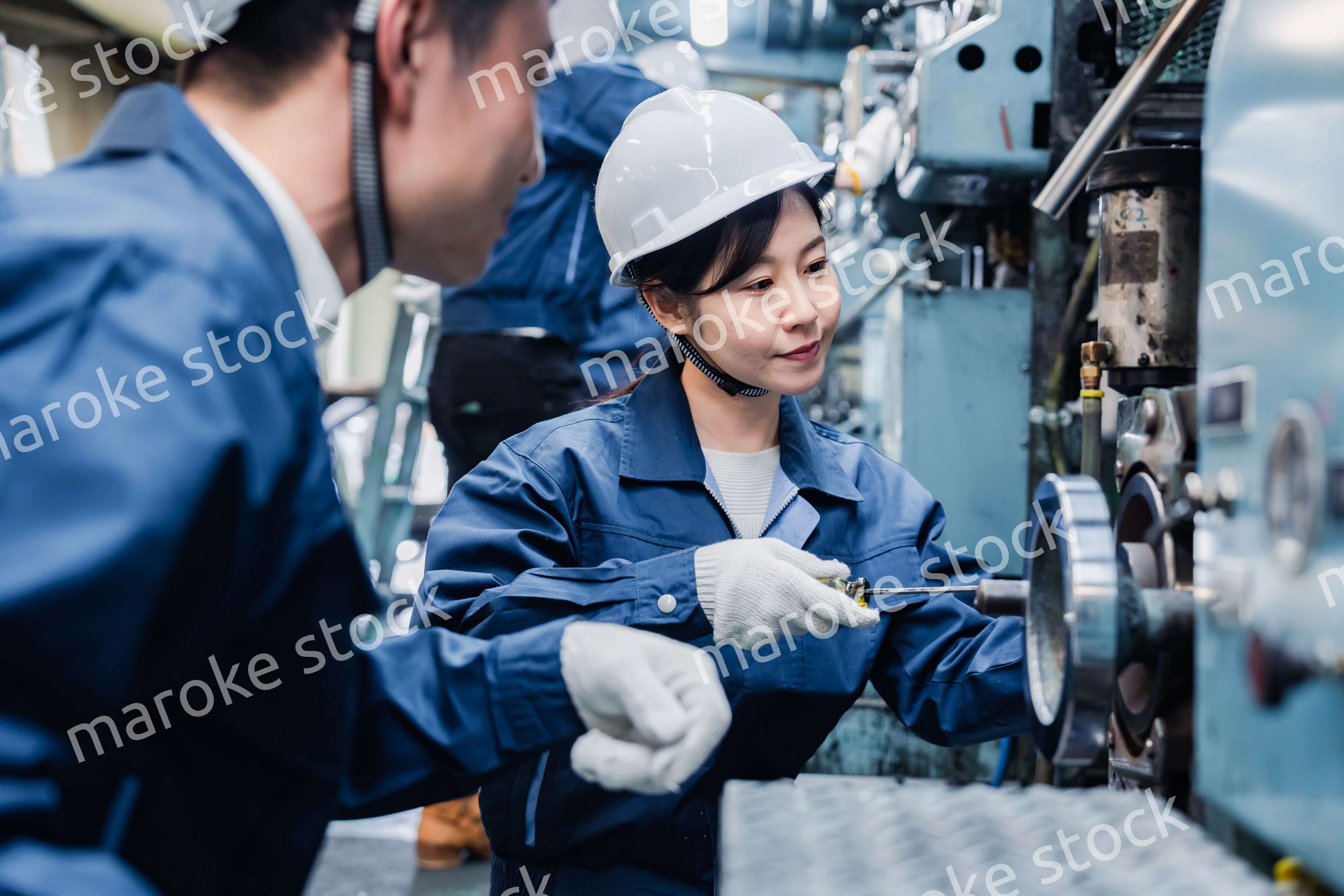 工場で作業を教えてもらう外国人労働者