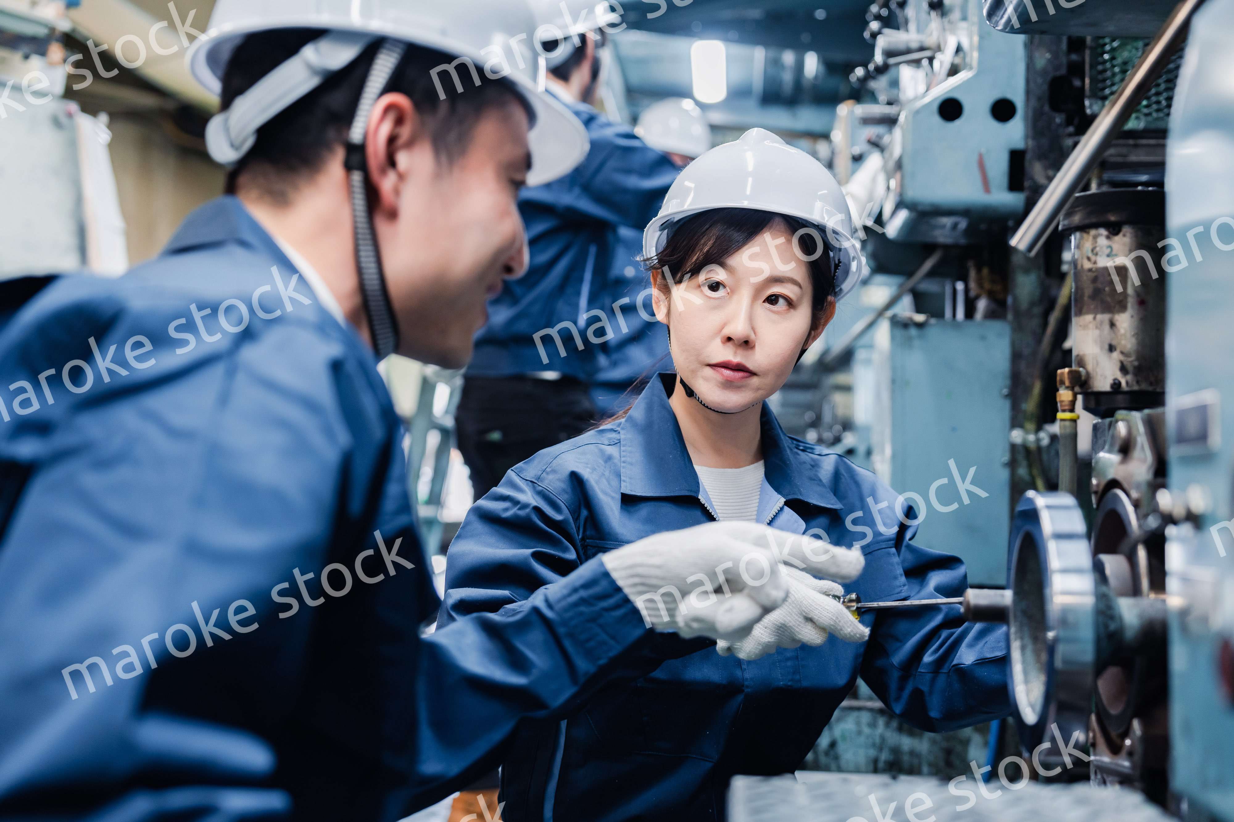 工場で作業を教えてもらう外国人労働者