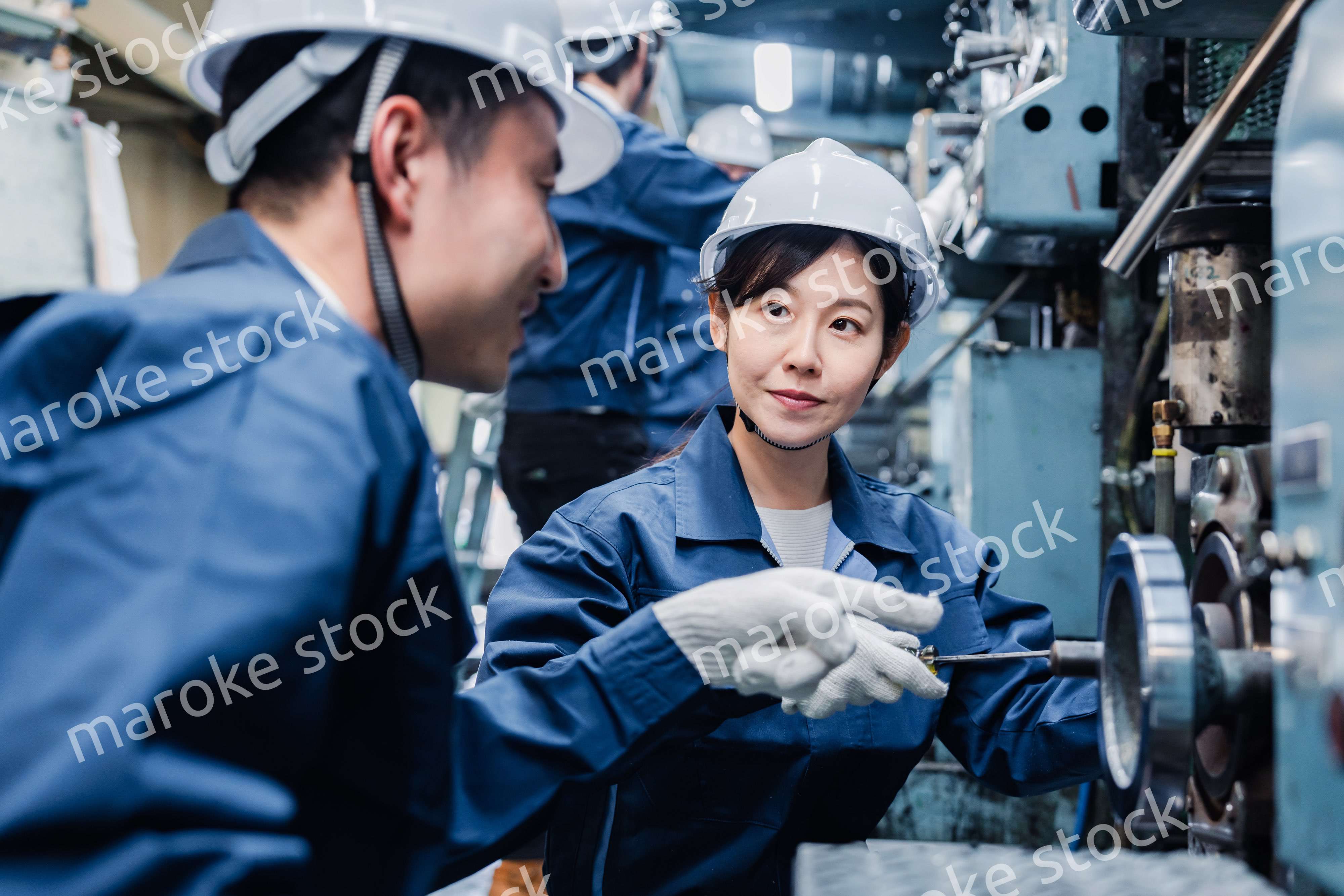 工場で作業を教えてもらう外国人労働者