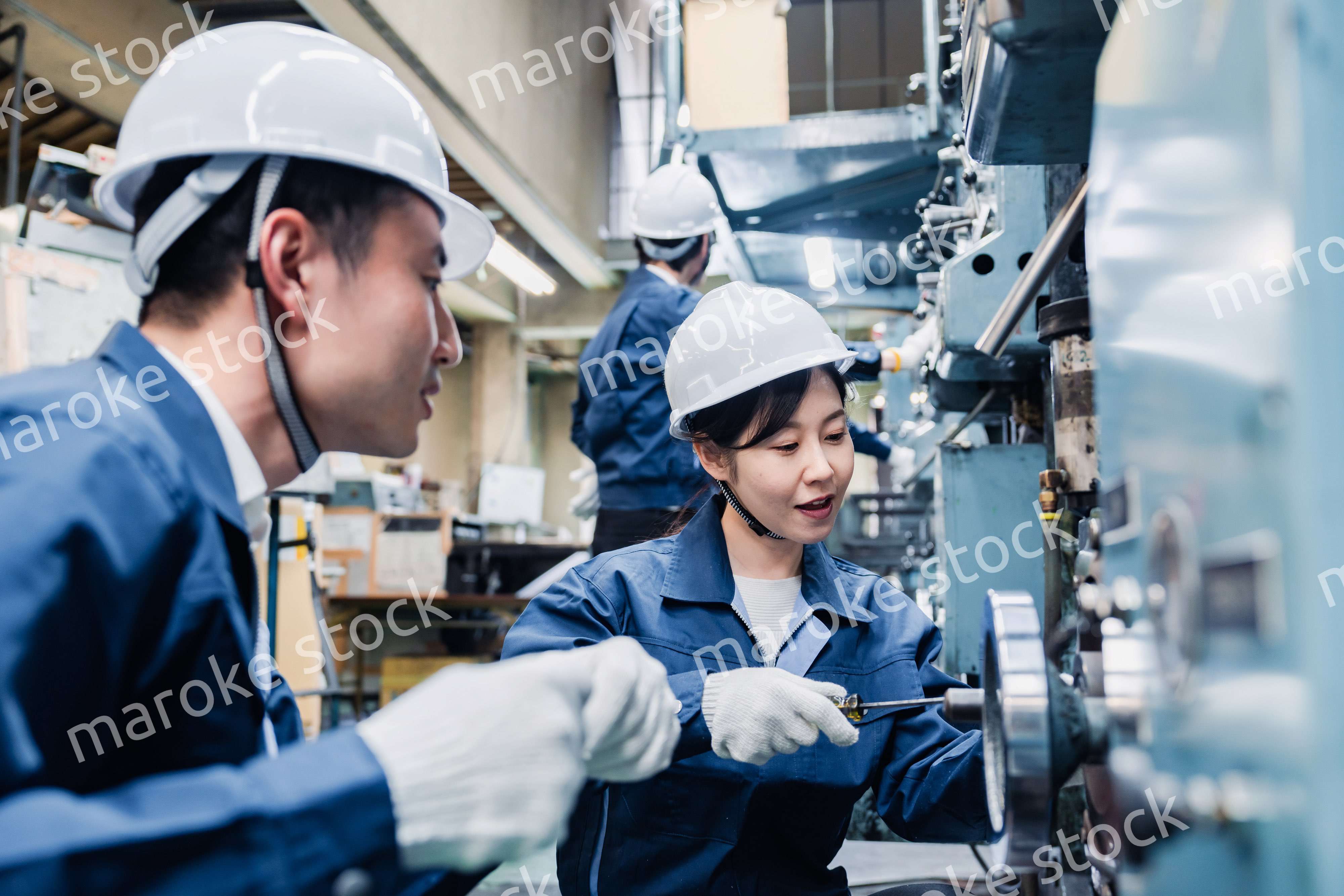 工場で作業を教えてもらう外国人労働者