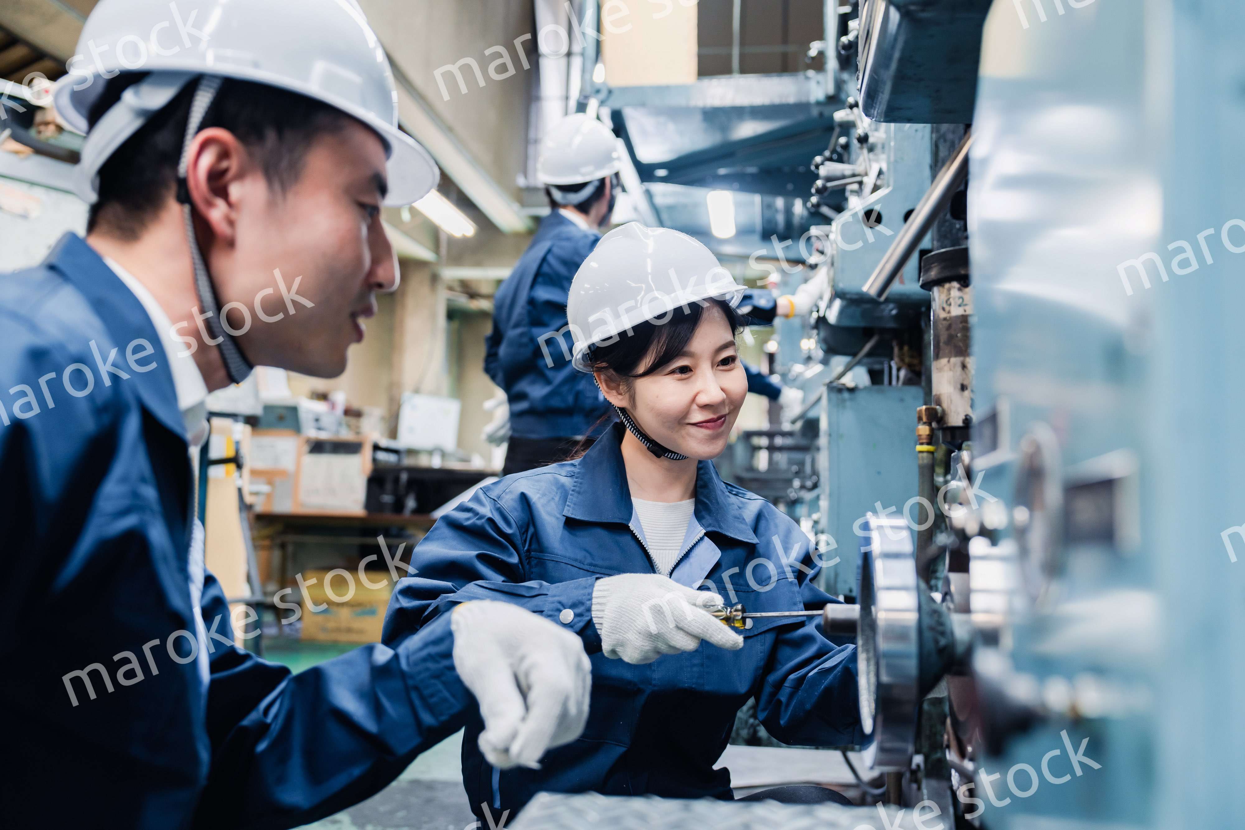 工場で作業を教えてもらう外国人労働者