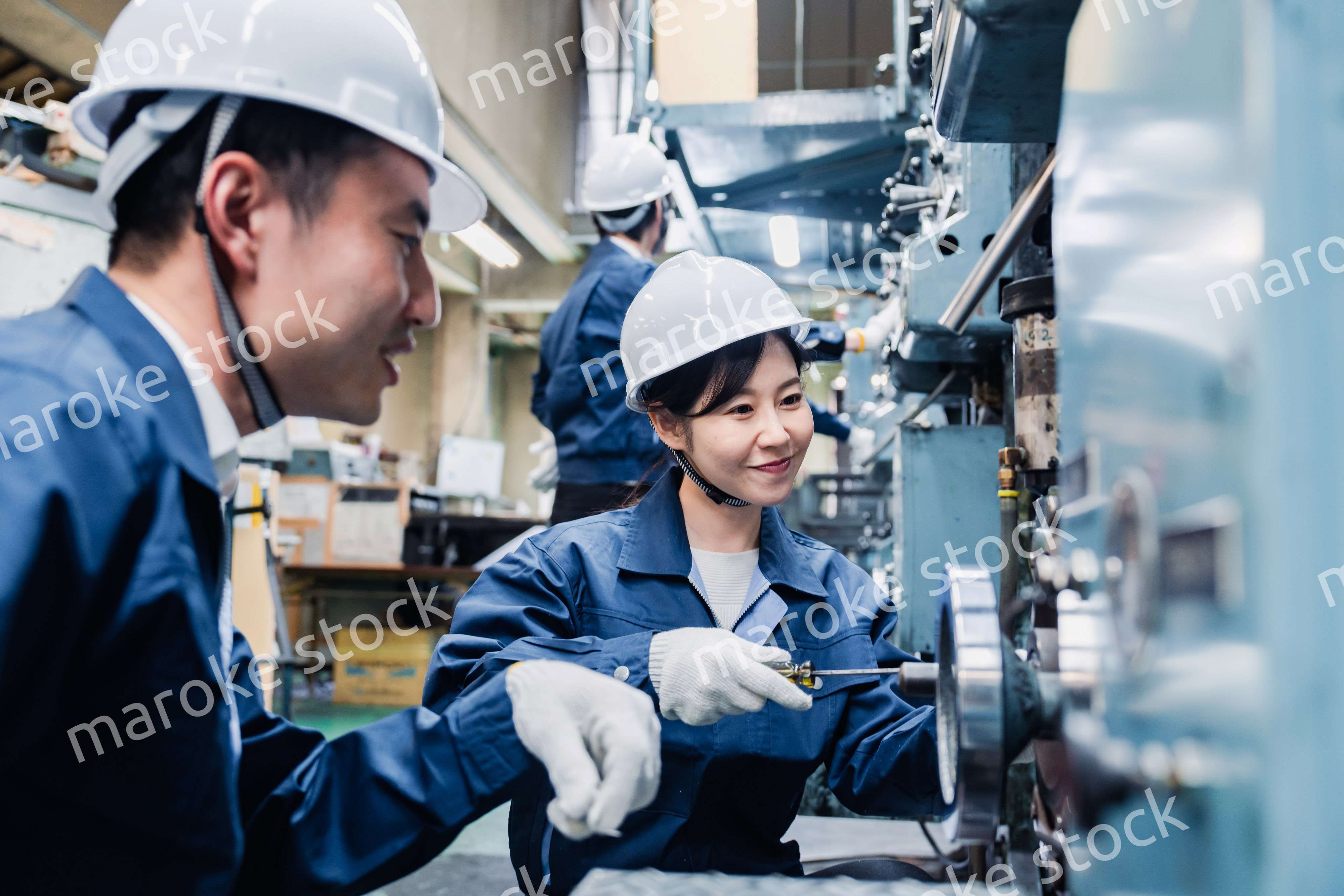 工場で作業を教えてもらう外国人労働者