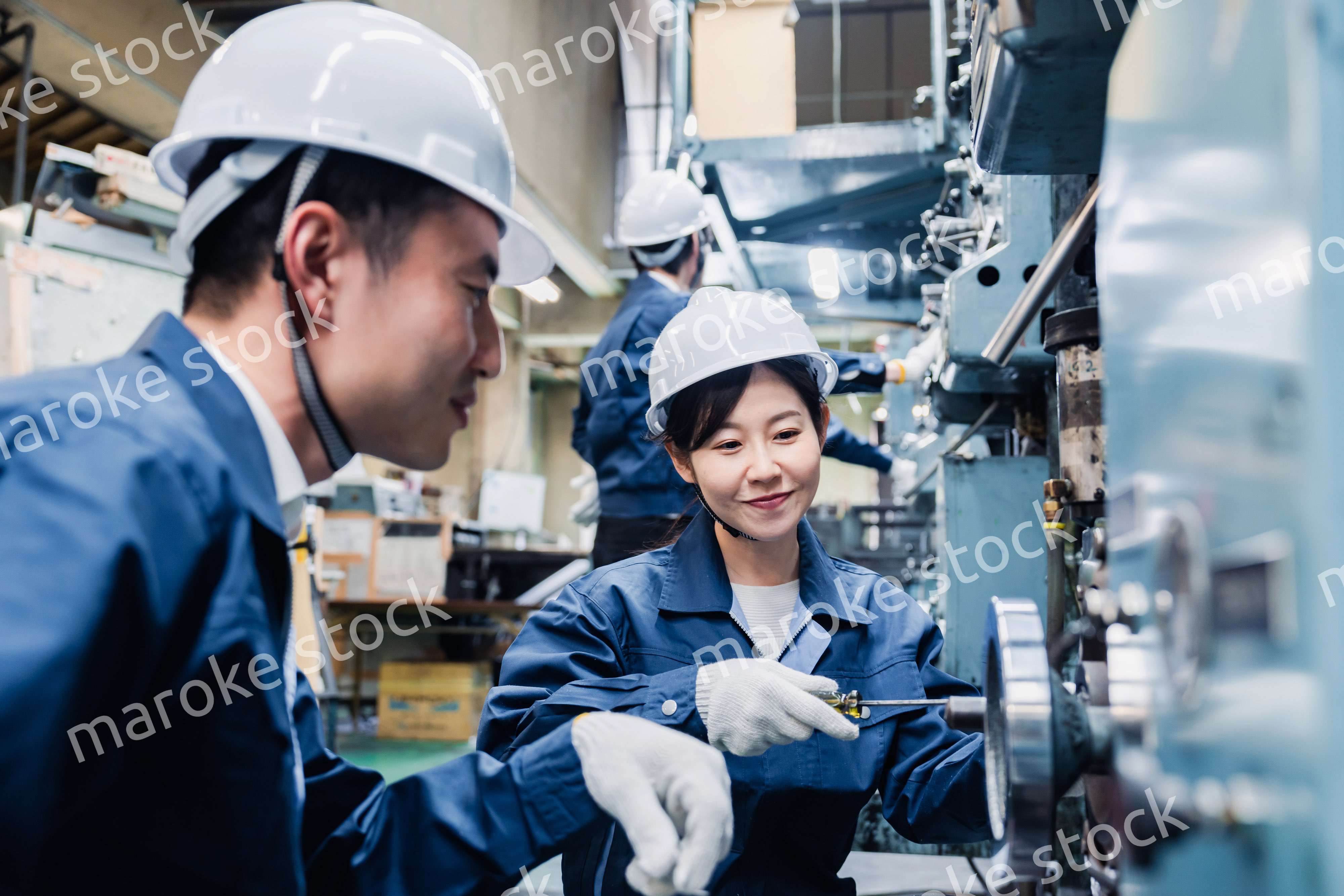 工場で作業を教えてもらう外国人労働者