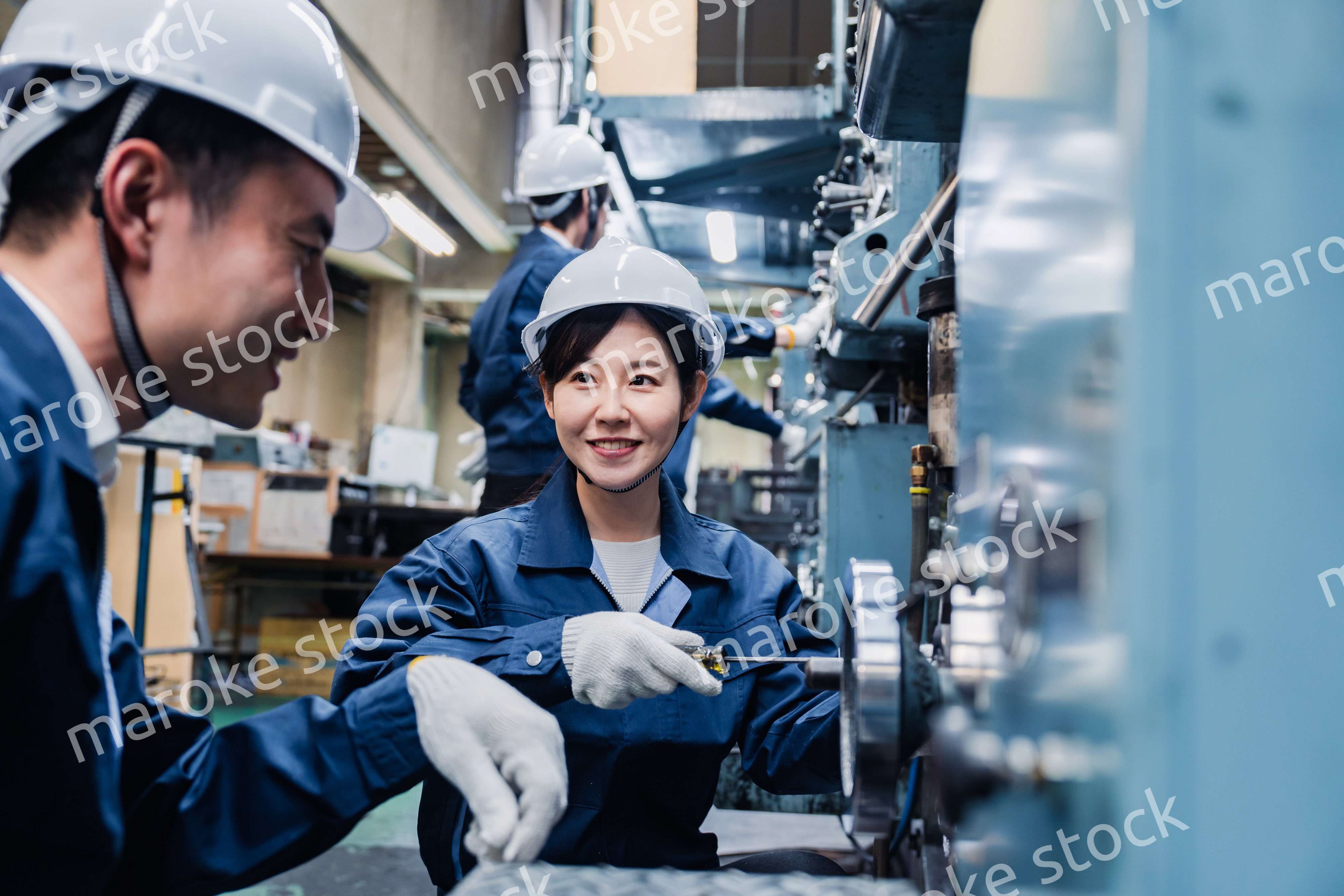 工場で作業を教えてもらう外国人労働者