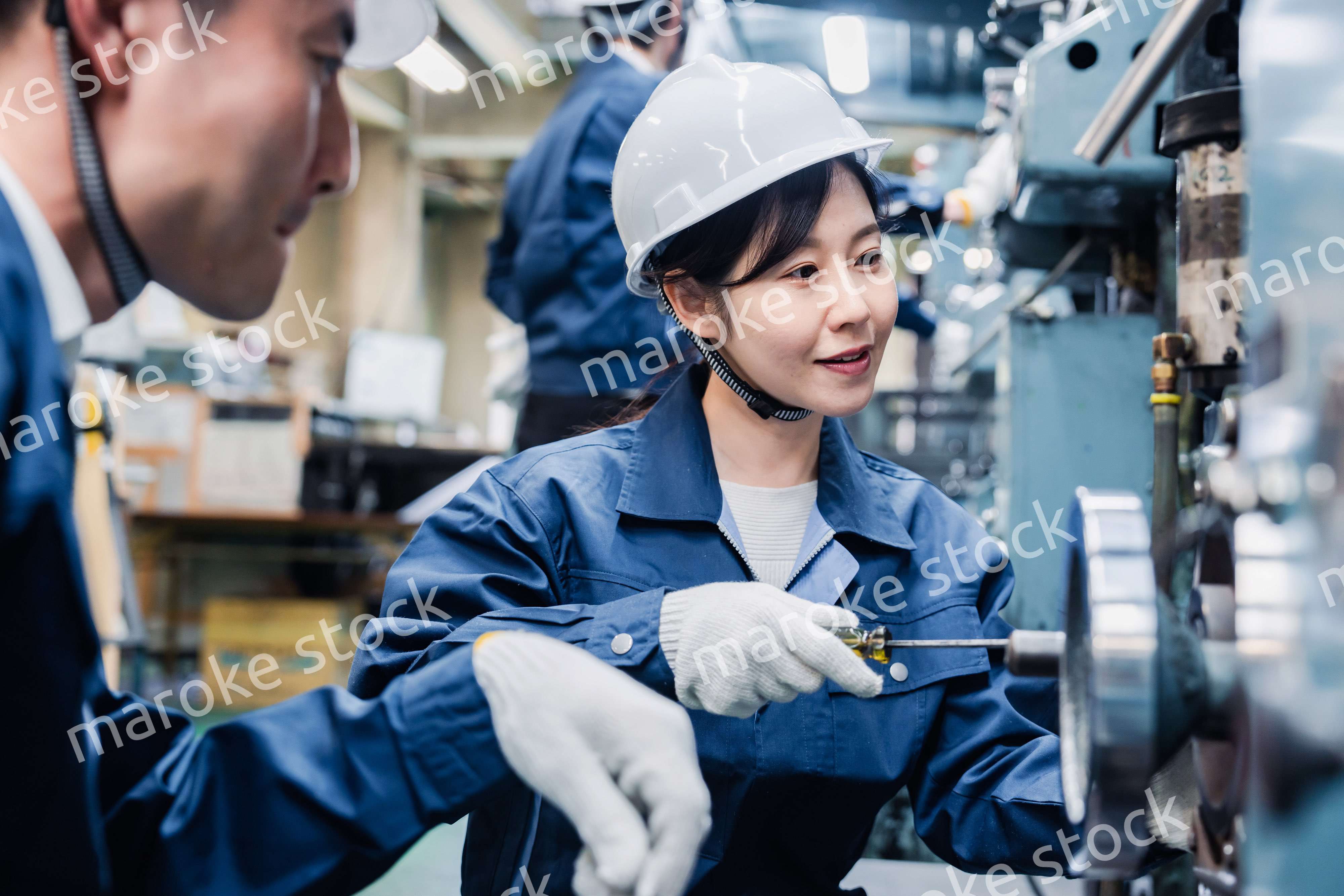 工場で作業を教えてもらう外国人労働者