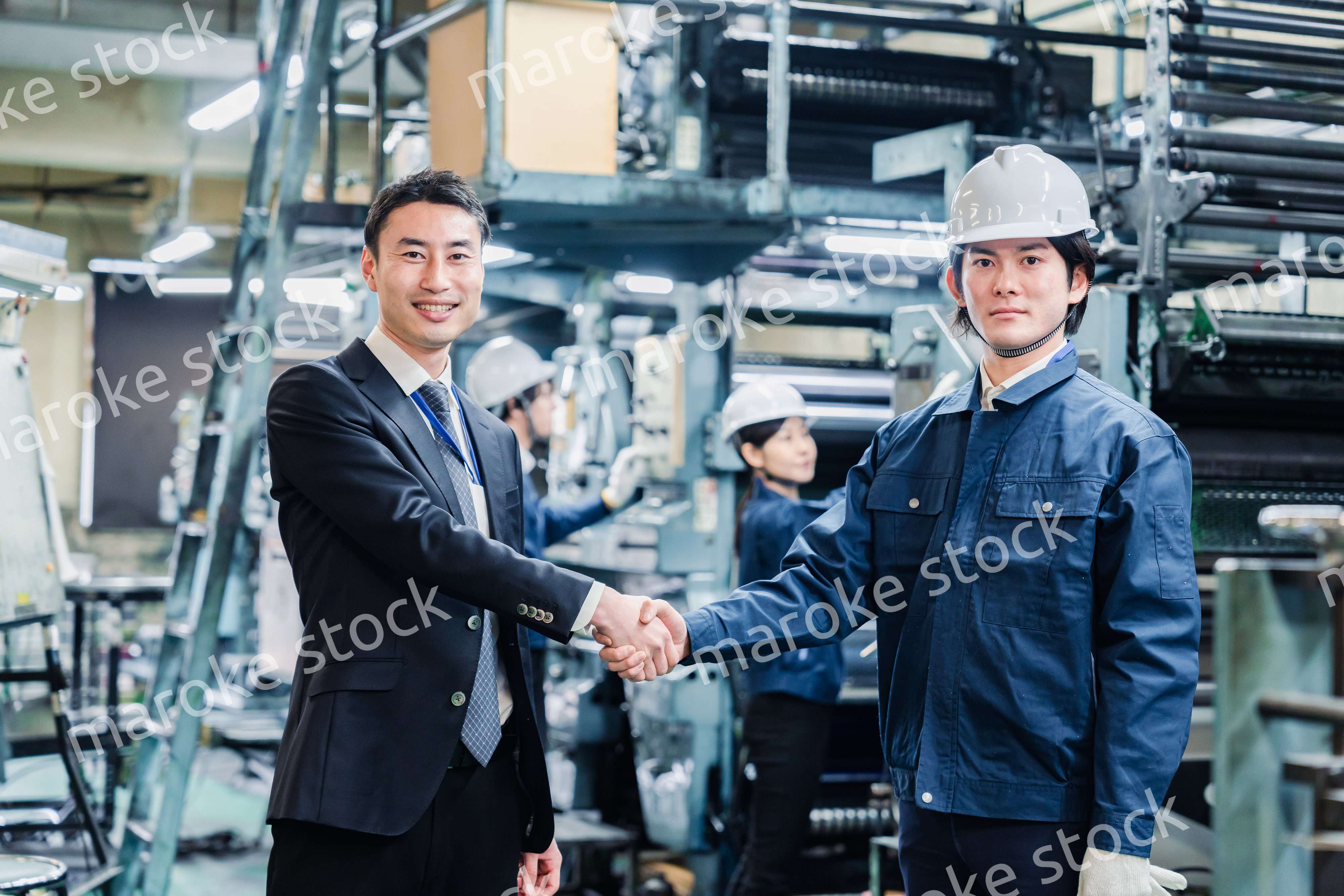 取引先と握手をする工場のスタッフ