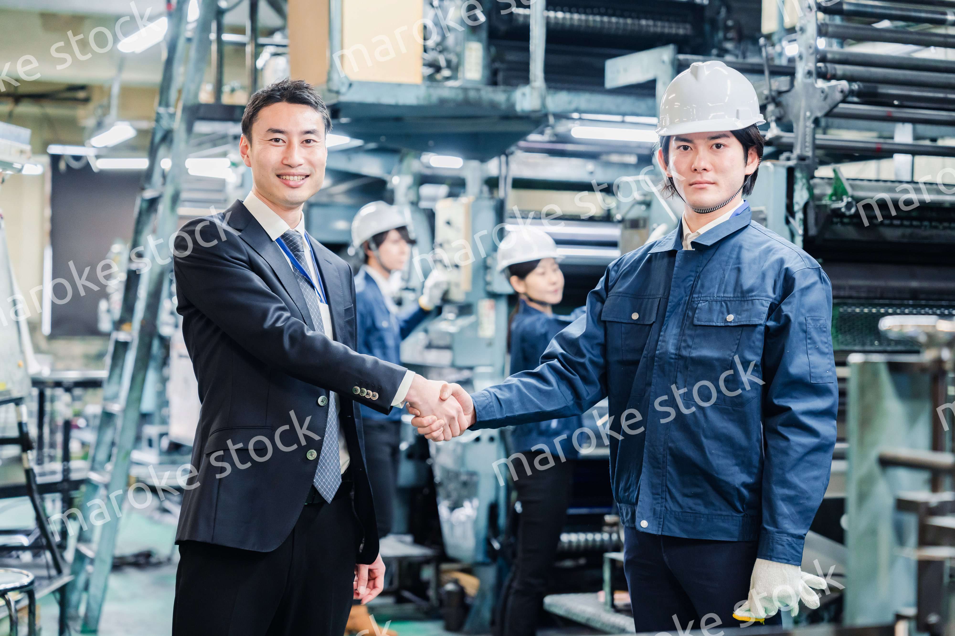 取引先と握手をする工場のスタッフ