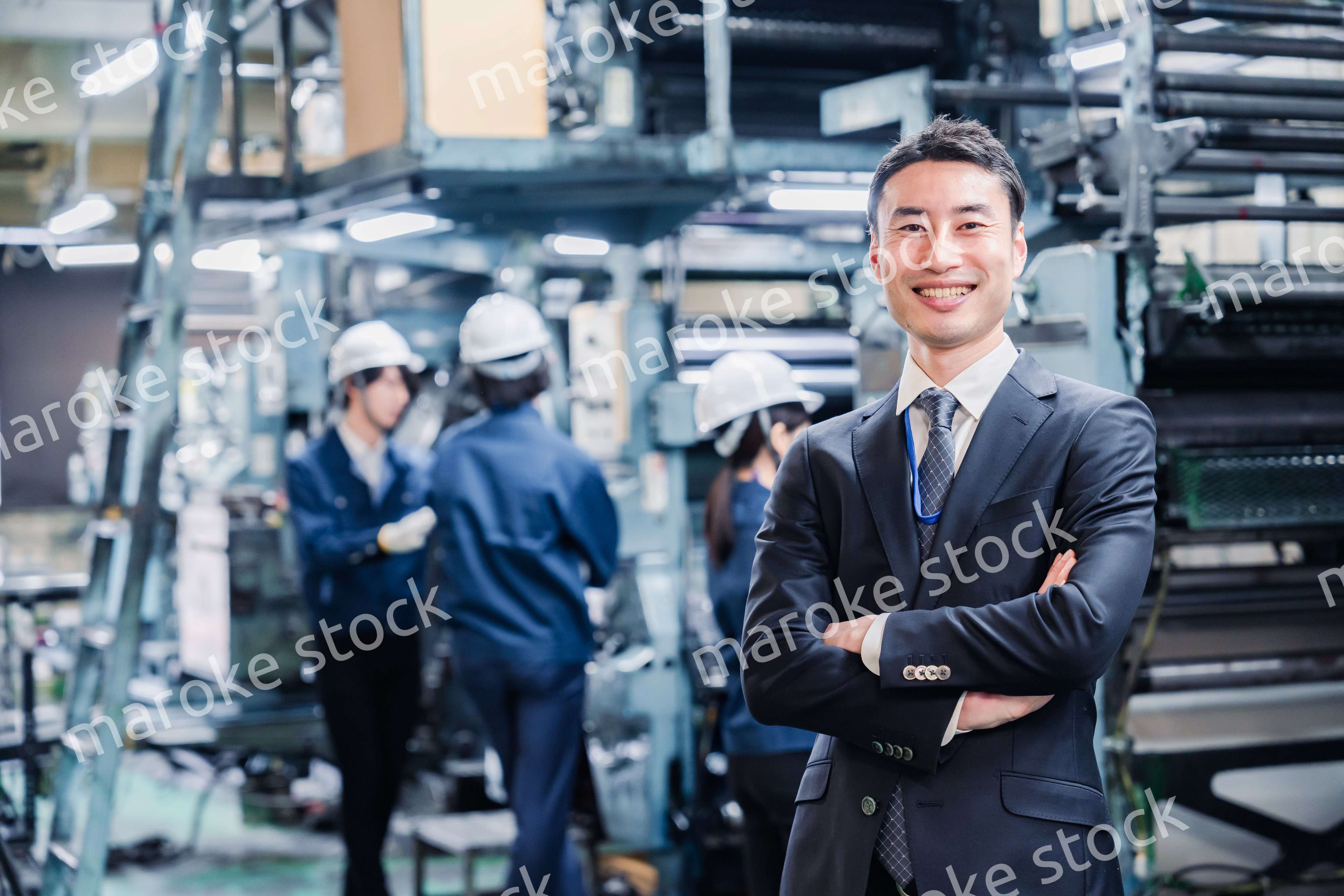 工場で腕を組むホワイトカラーの男性