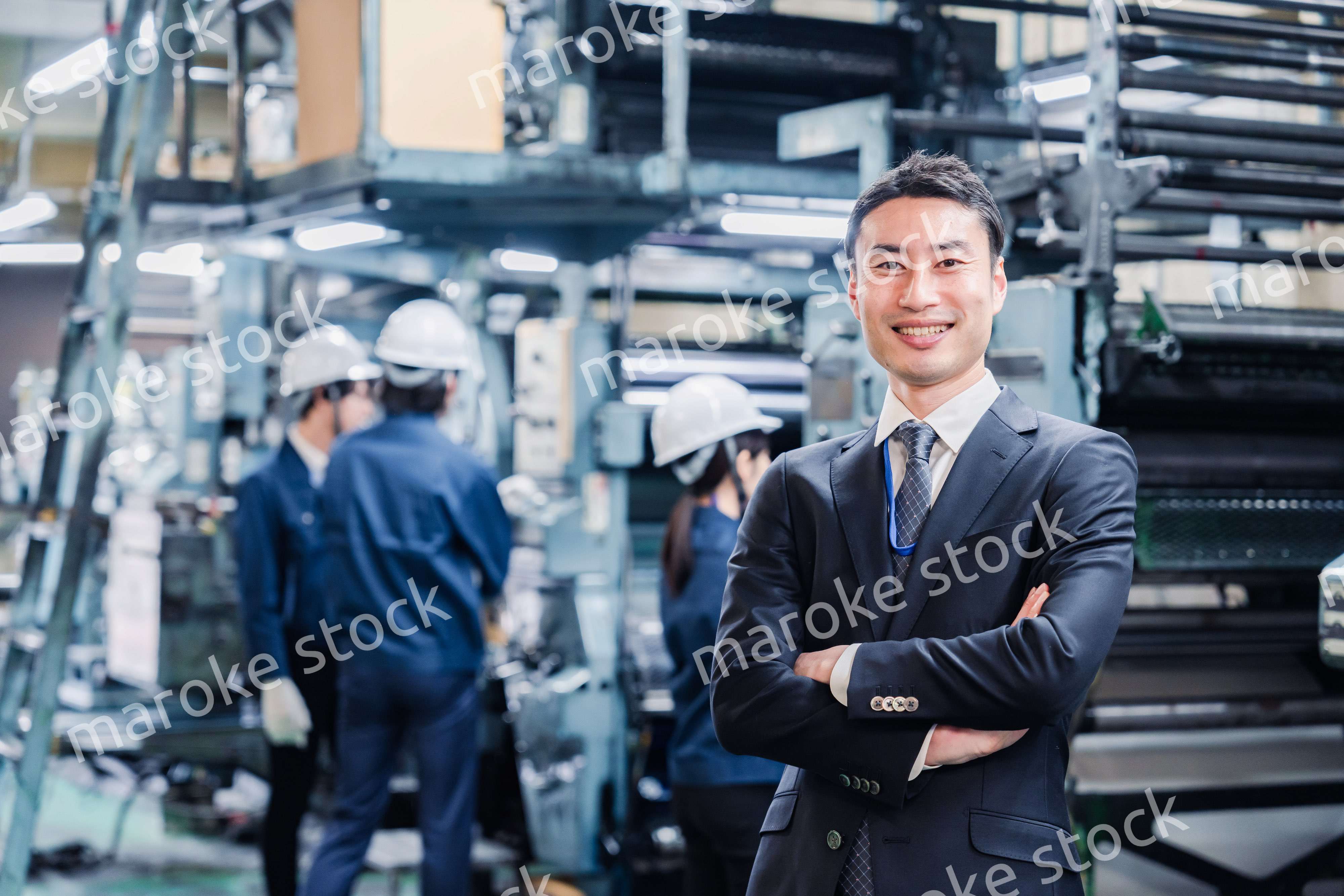 工場で腕を組むホワイトカラーの男性