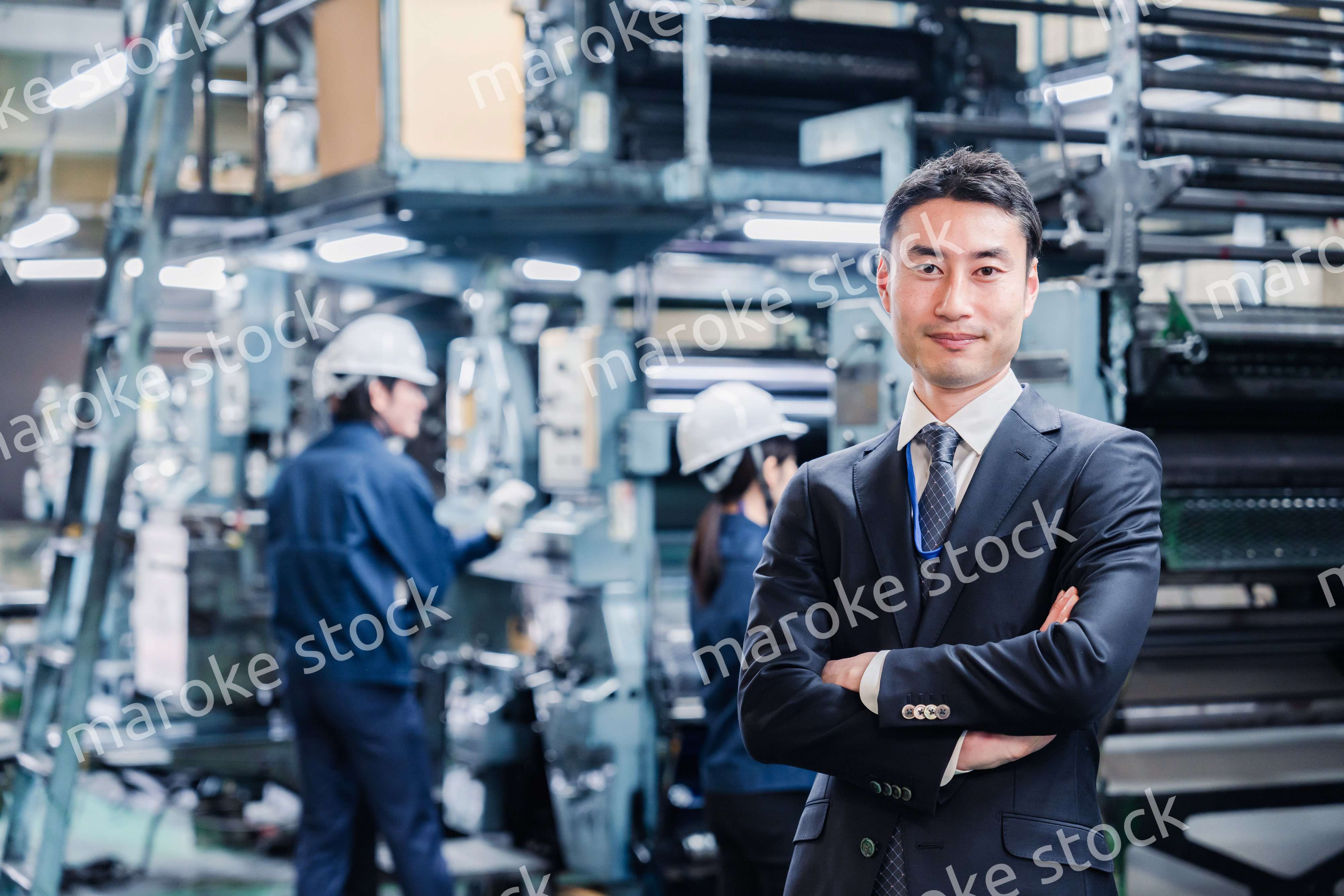 工場で腕を組むホワイトカラーの男性