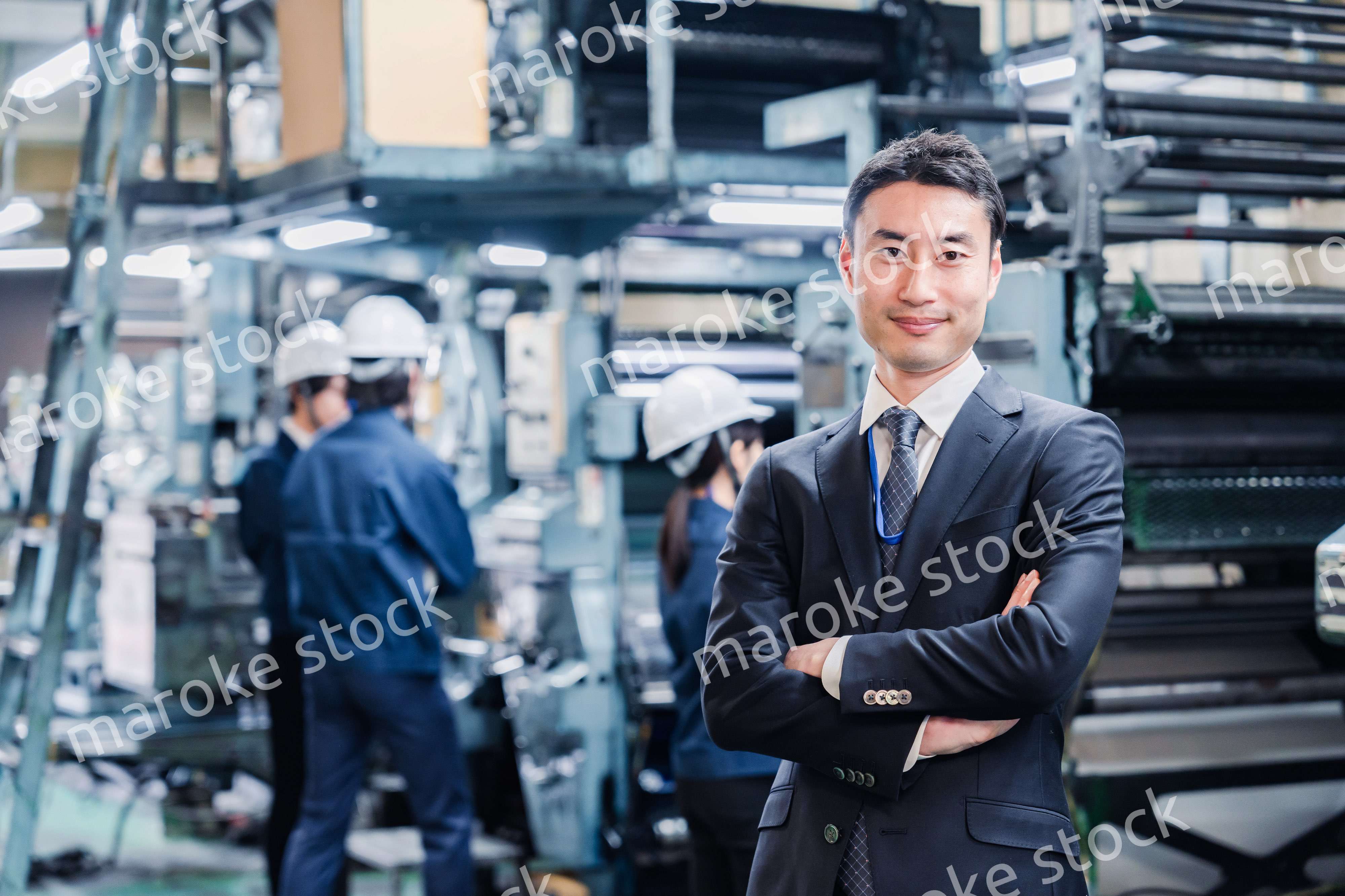 工場で腕を組むホワイトカラーの男性