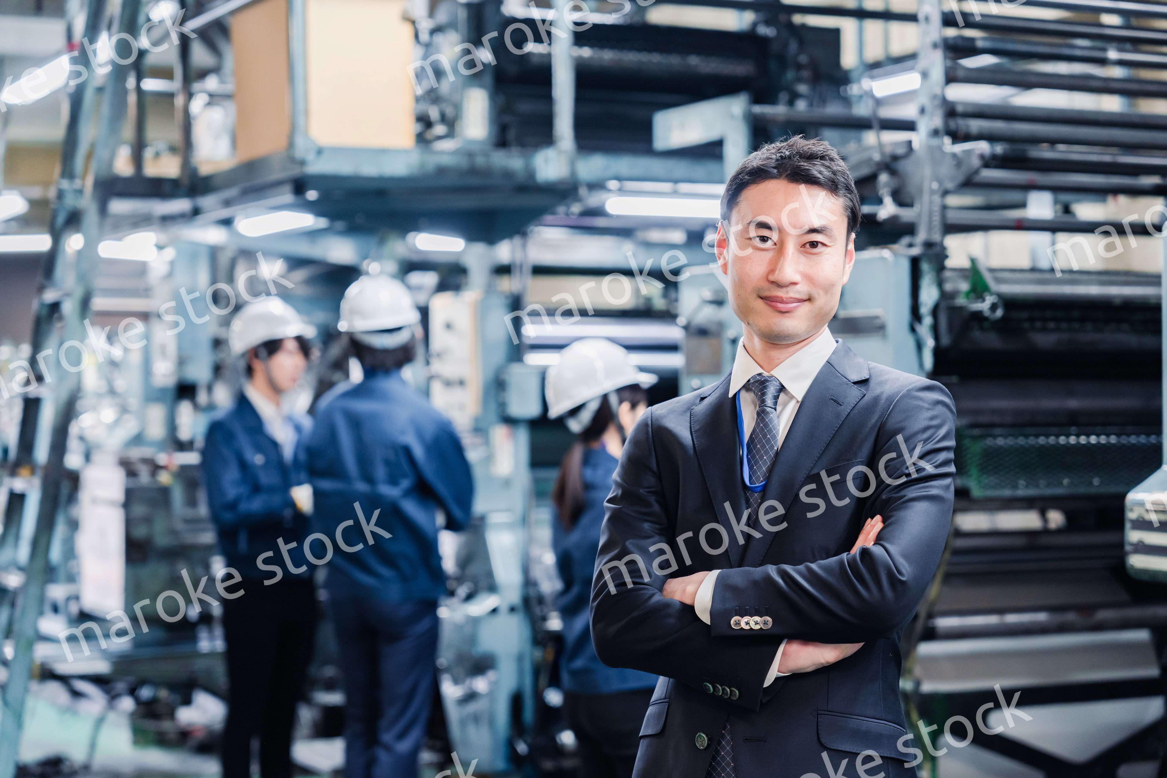 工場で腕を組むホワイトカラーの男性