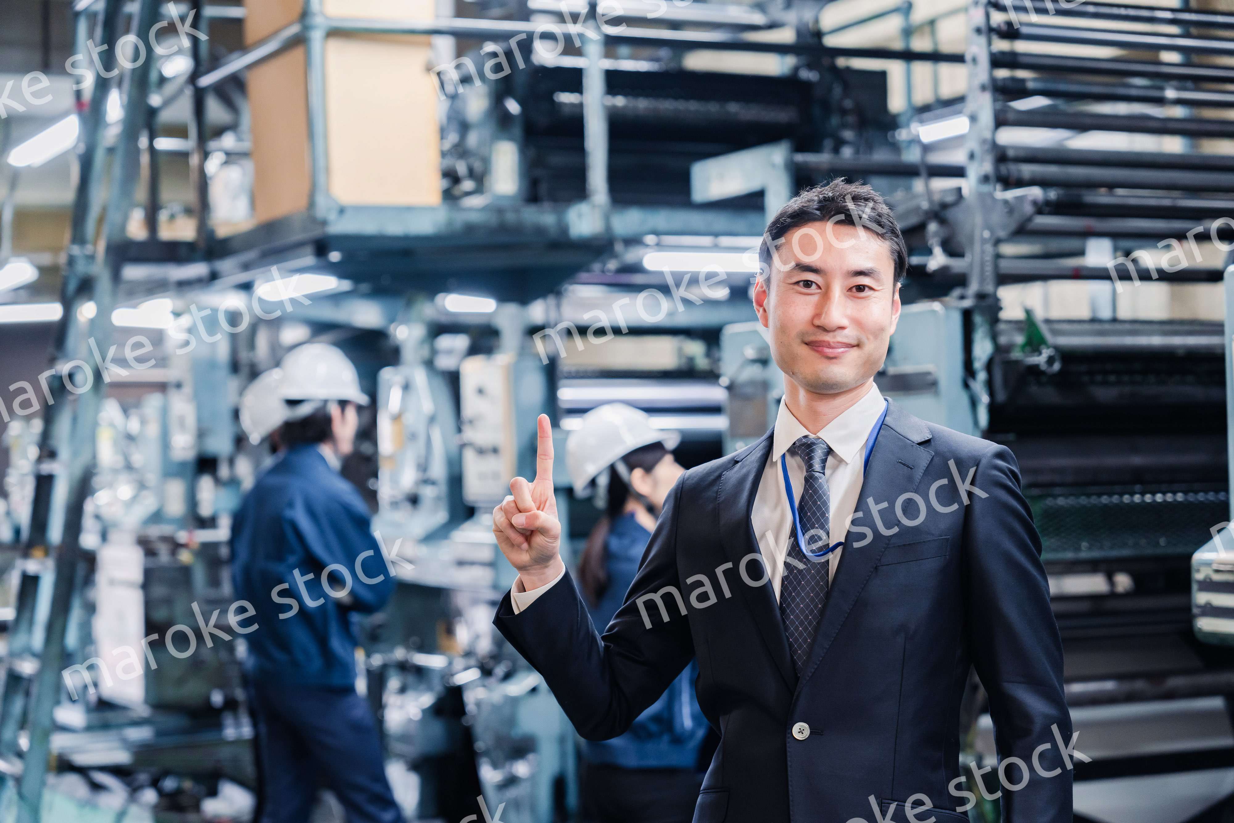 工場で指を指すビジネスマン
