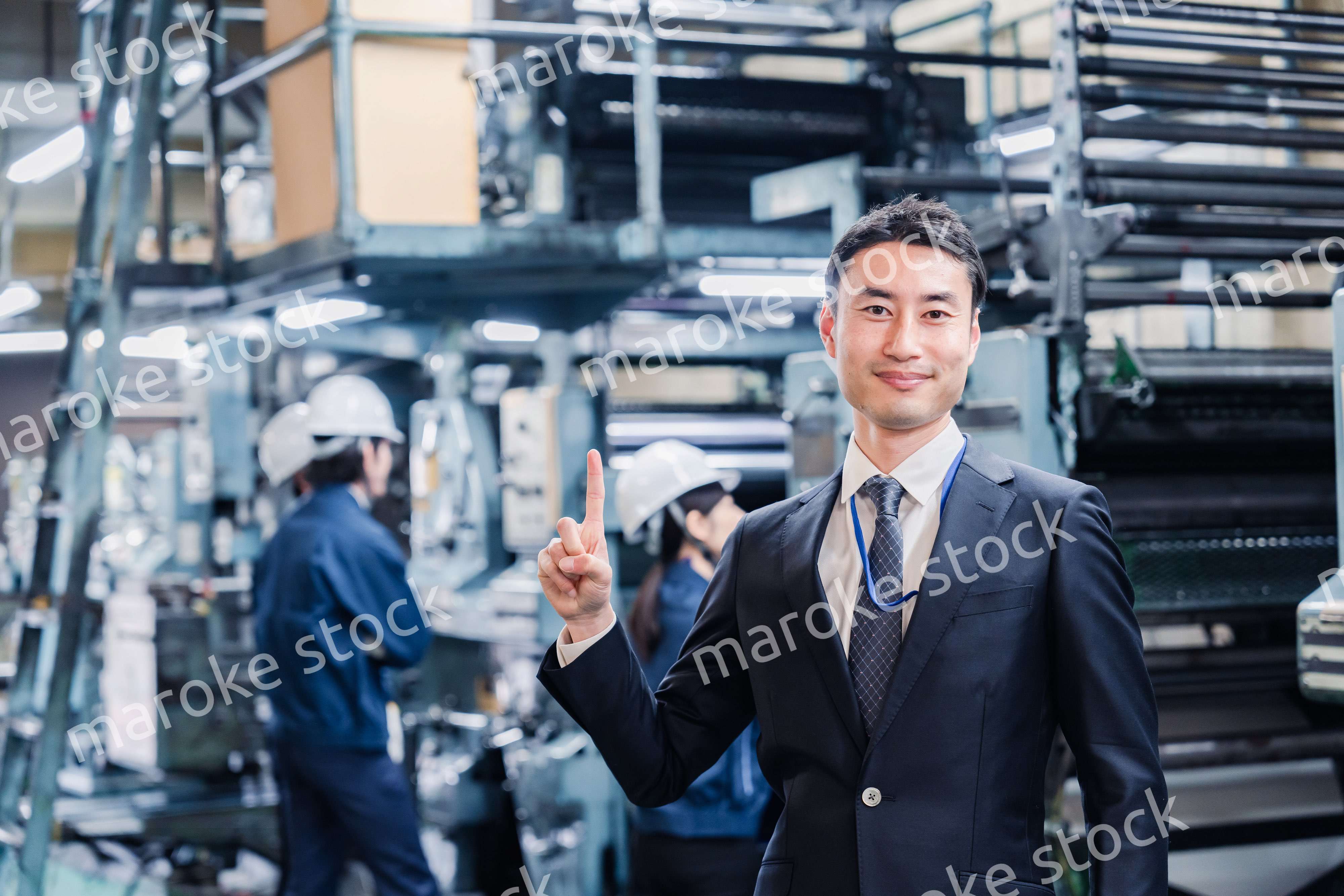 工場で指を指すビジネスマン
