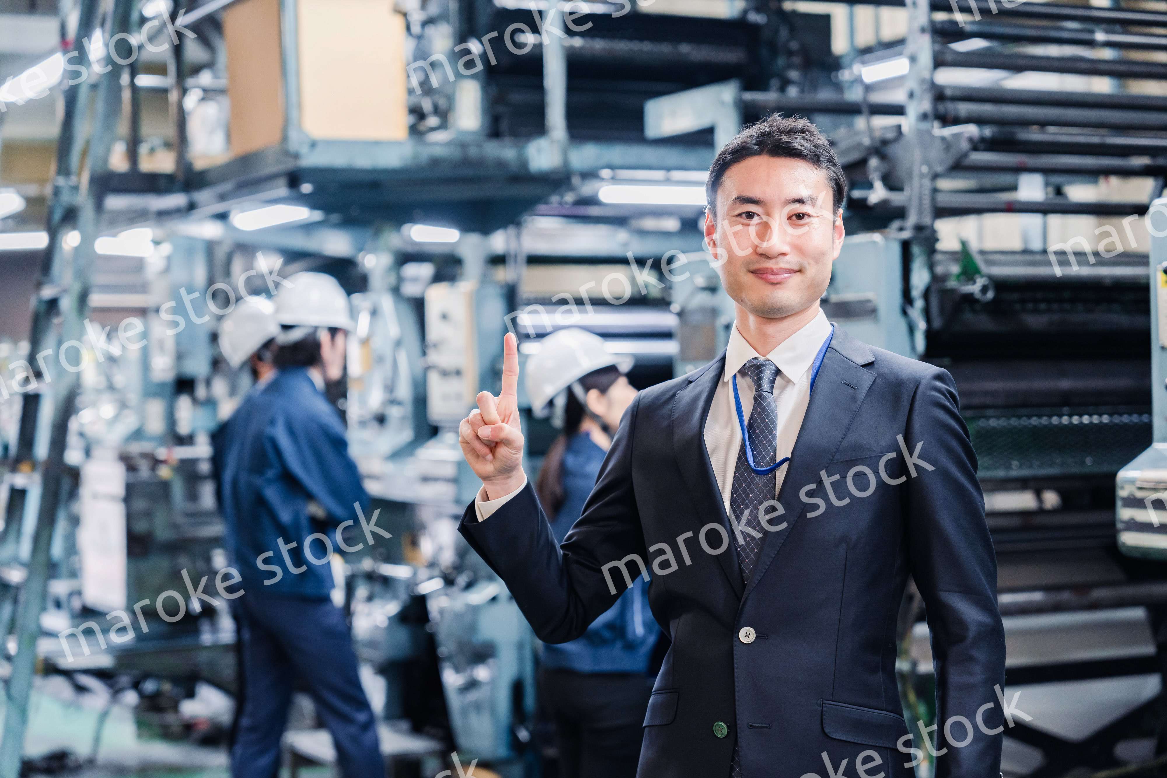工場で指を指すビジネスマン