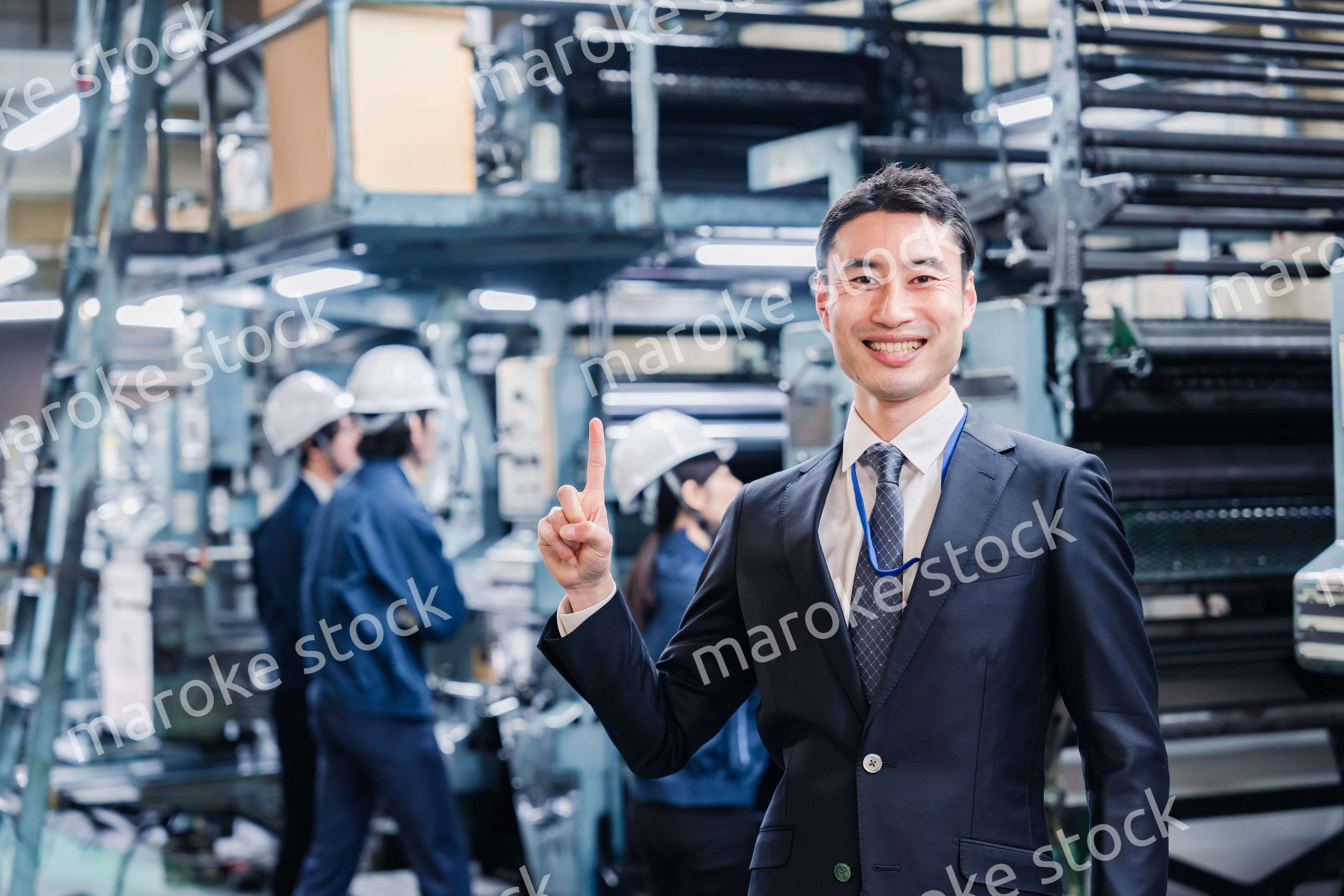 工場で指を指すビジネスマン