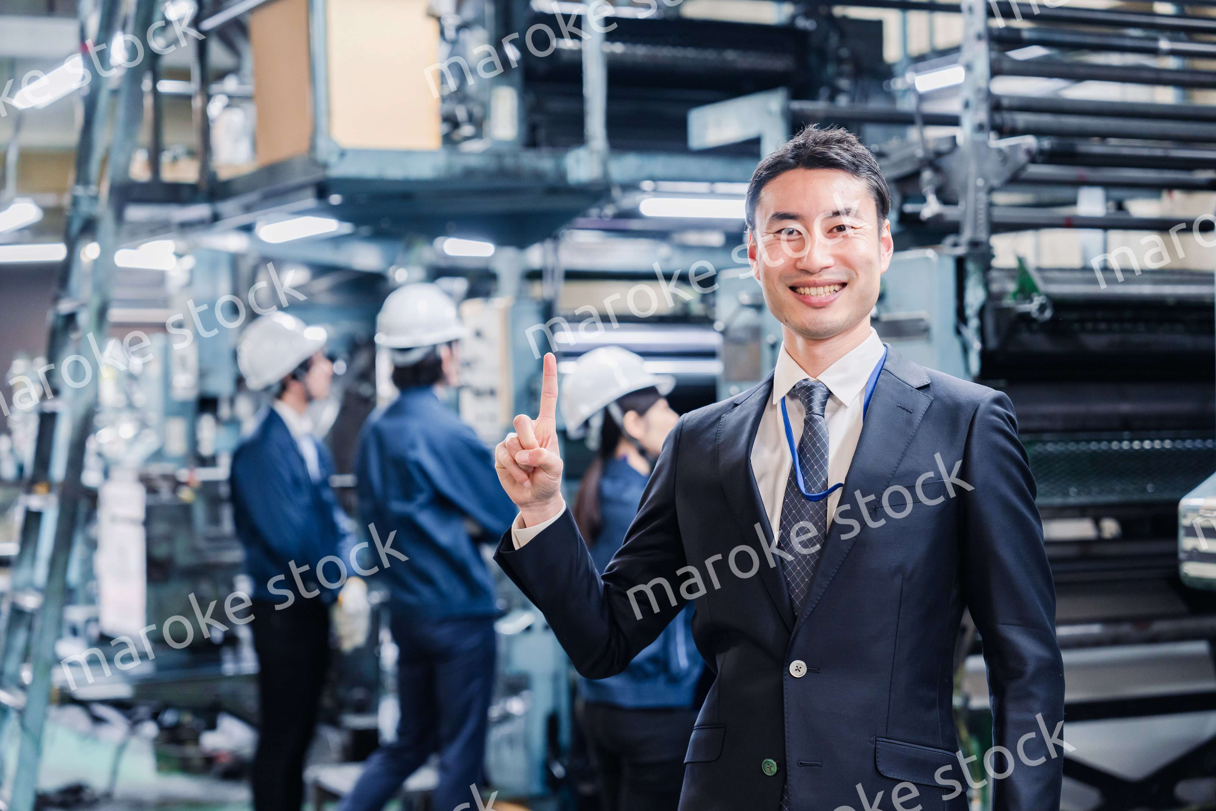工場で指を指すビジネスマン