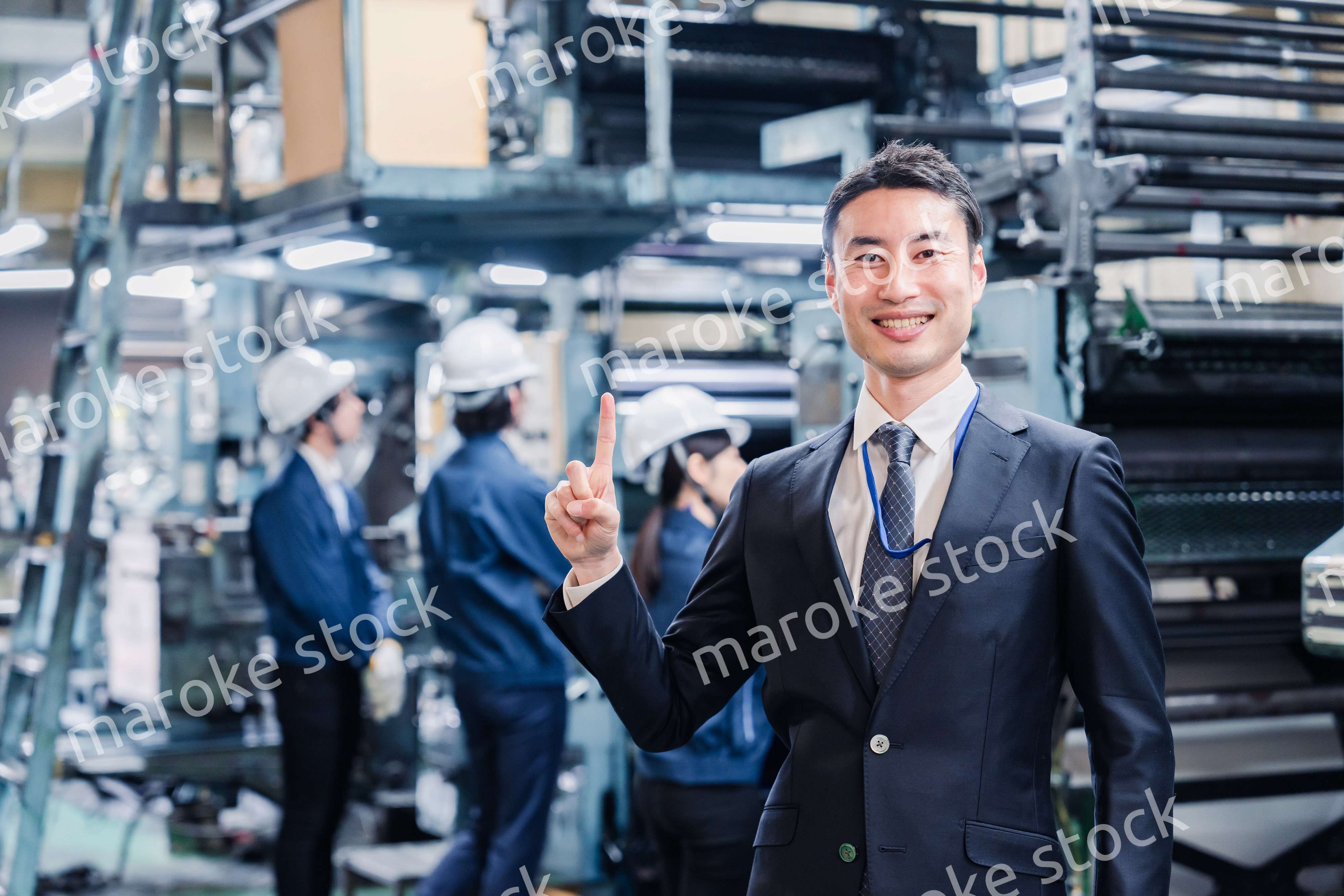 工場で指を指すビジネスマン
