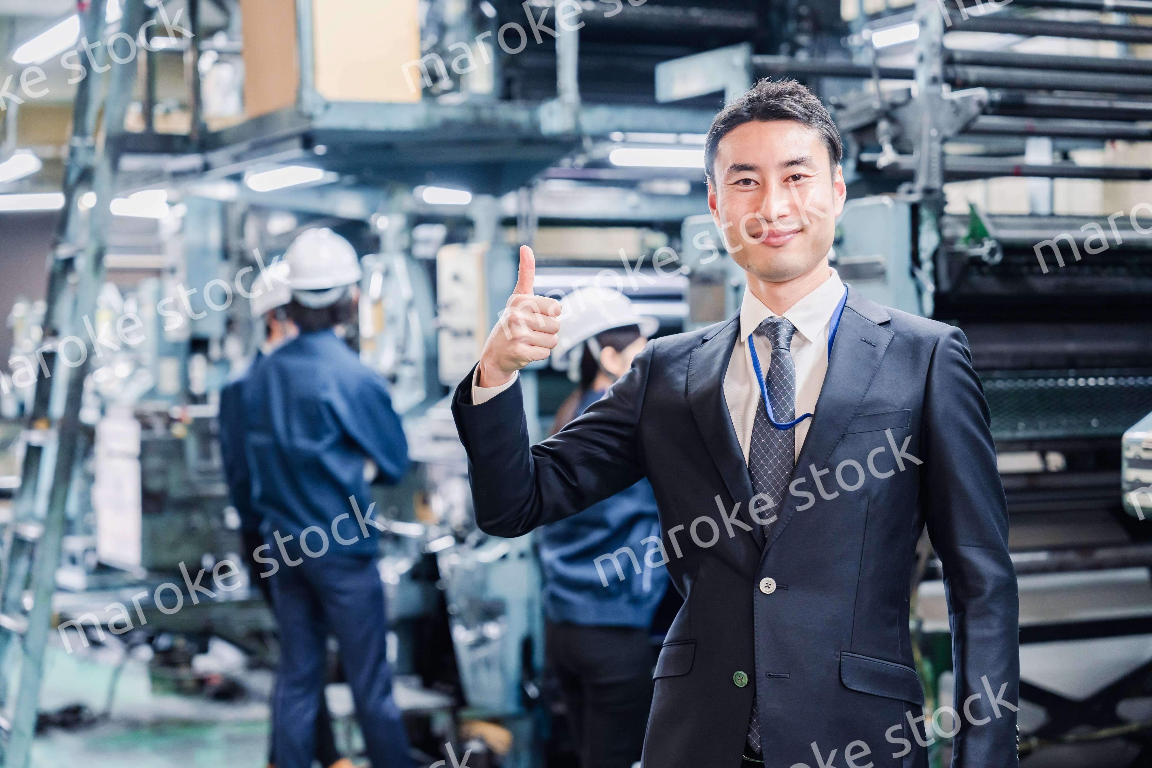 工場でOKサインをするビジネスマン