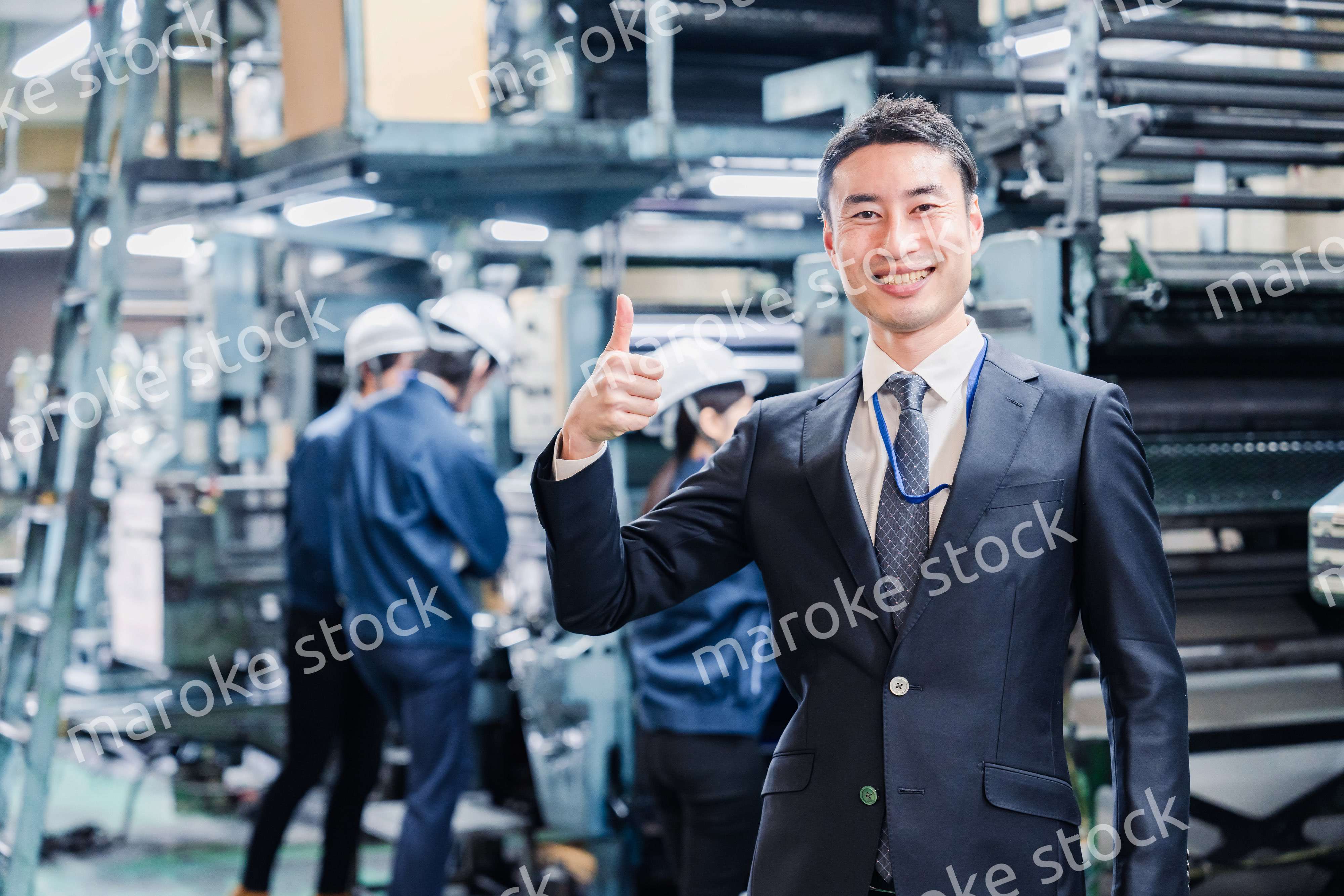 工場でOKサインをするビジネスマン