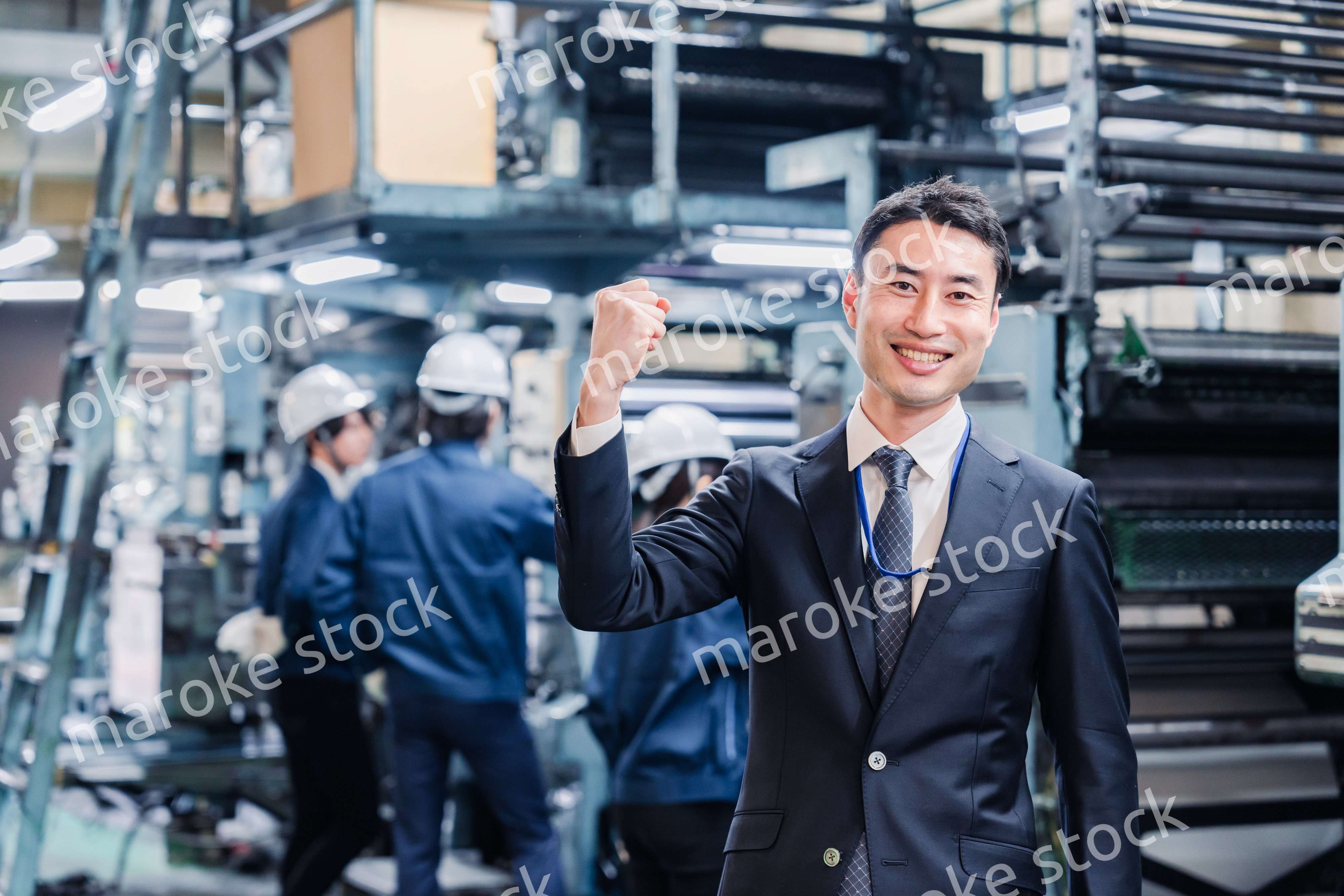 工場でガッツポーズをするビジネスマン