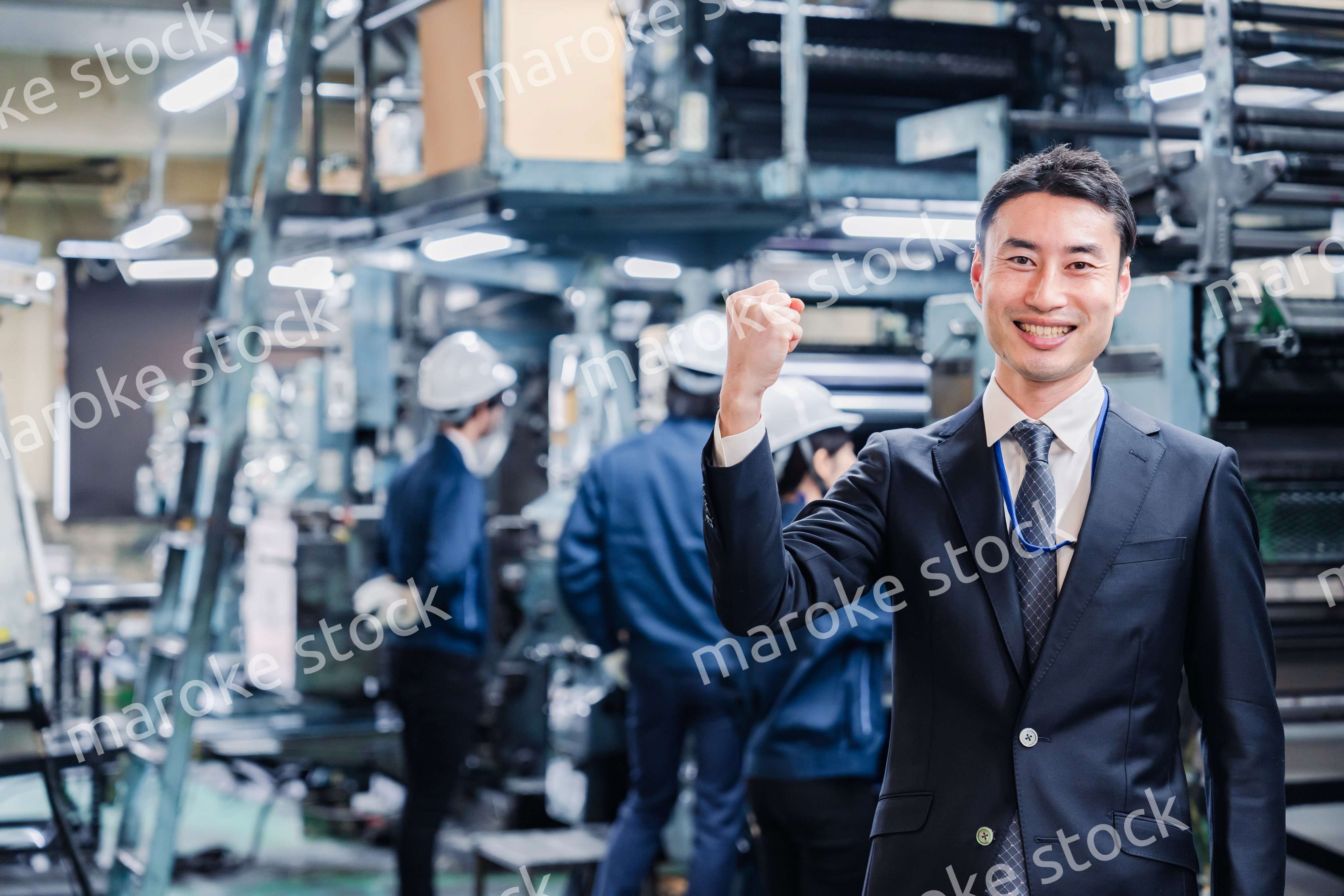 工場でガッツポーズをするビジネスマン