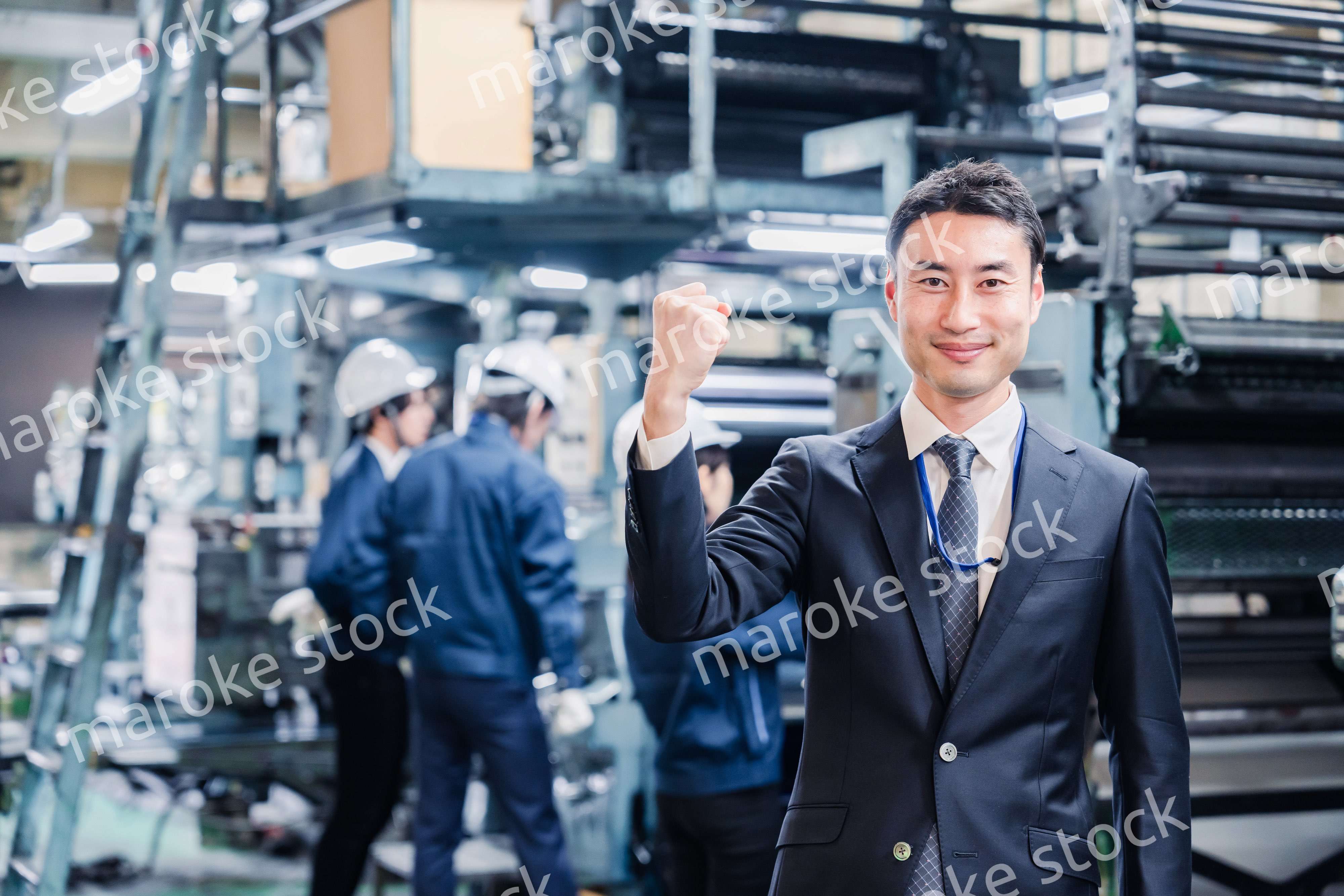 工場でガッツポーズをするビジネスマン