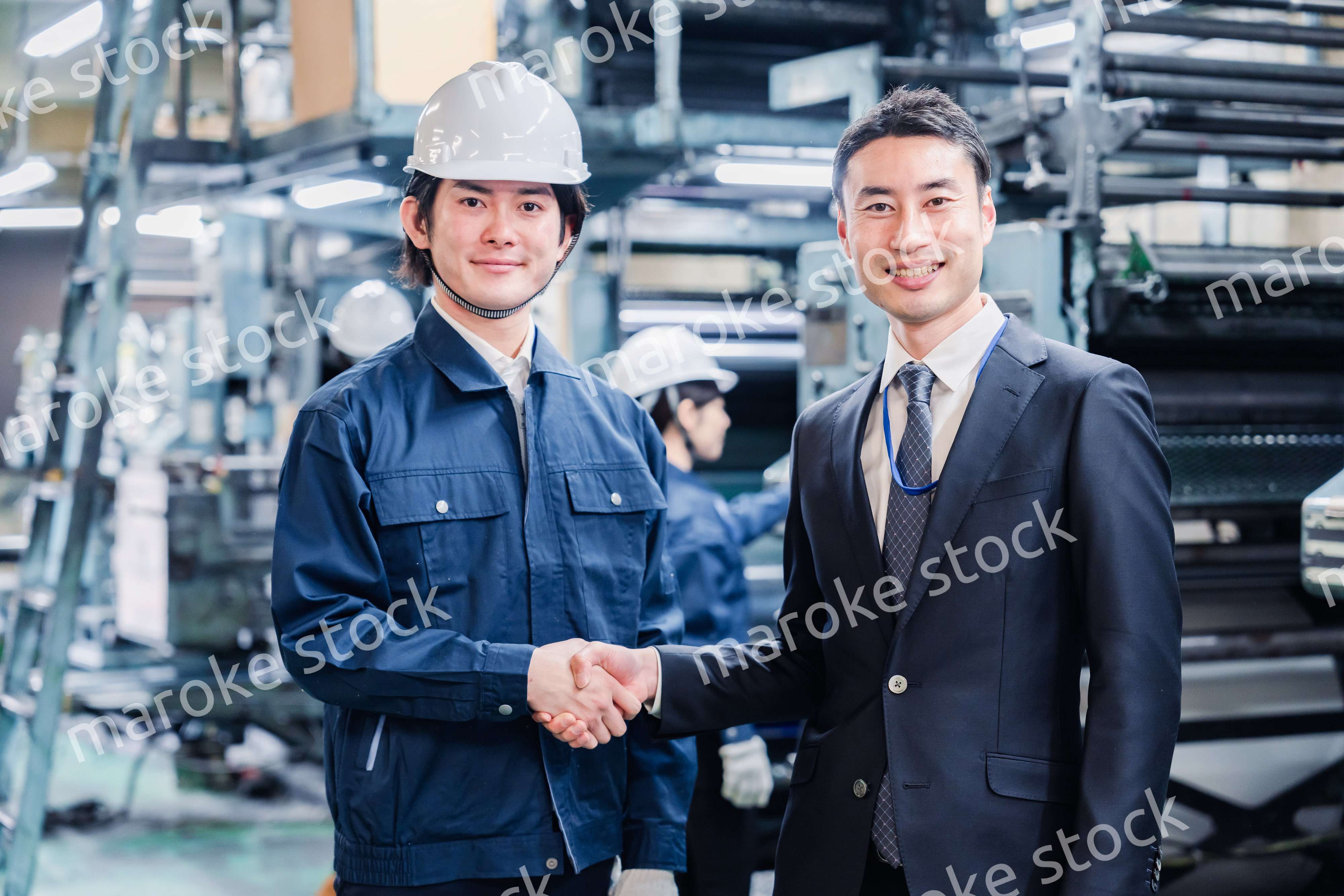 工場で握手をするビジネスマン