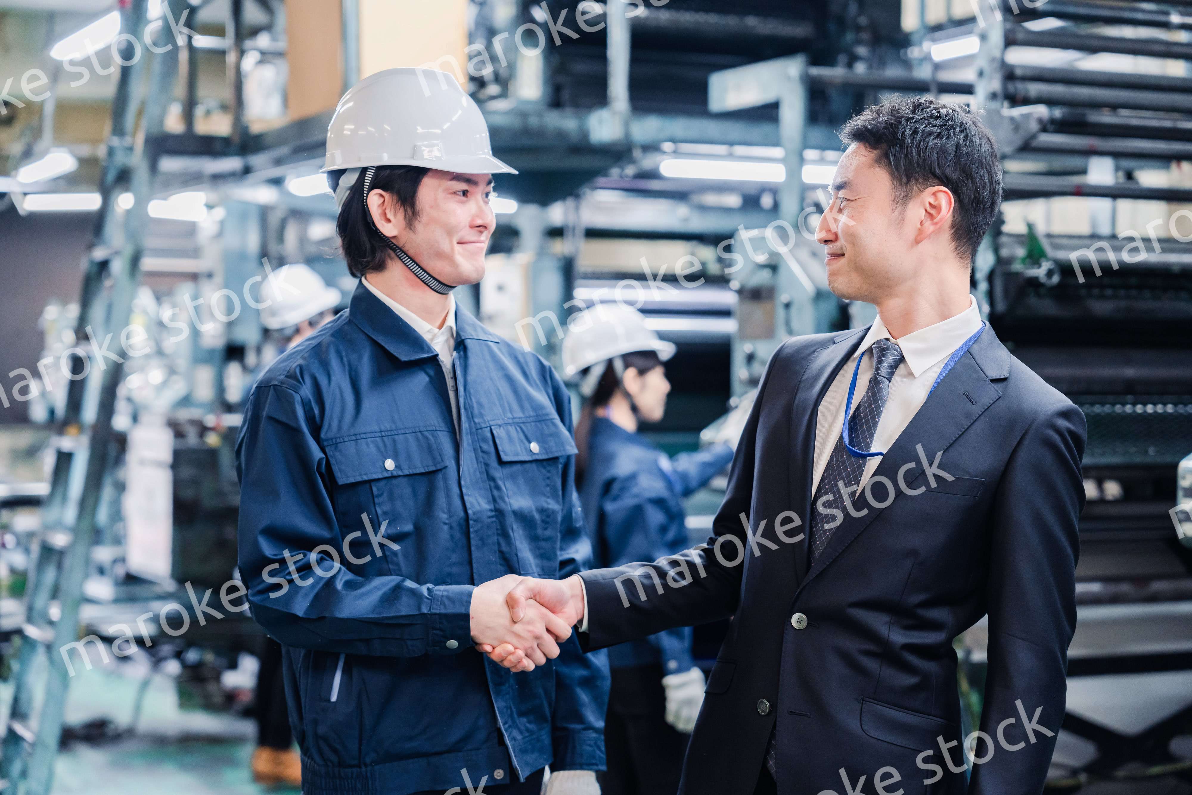 工場で握手をするビジネスマン