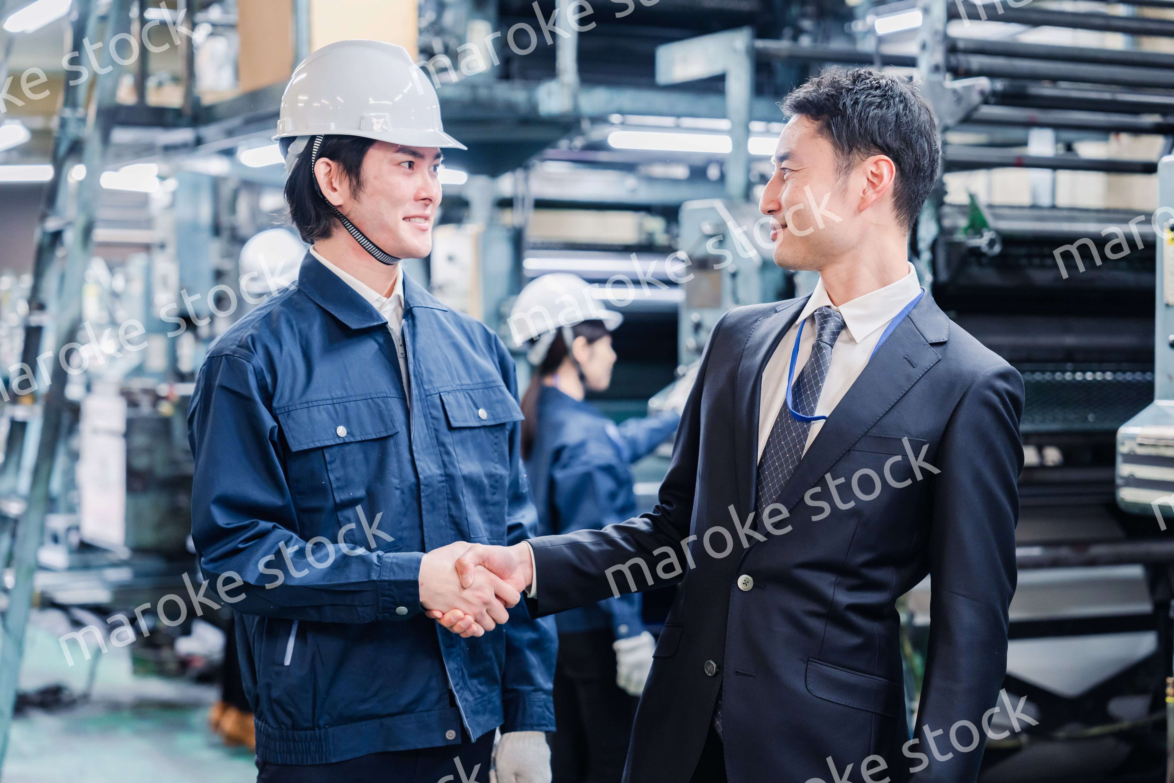 工場で握手をするビジネスマン