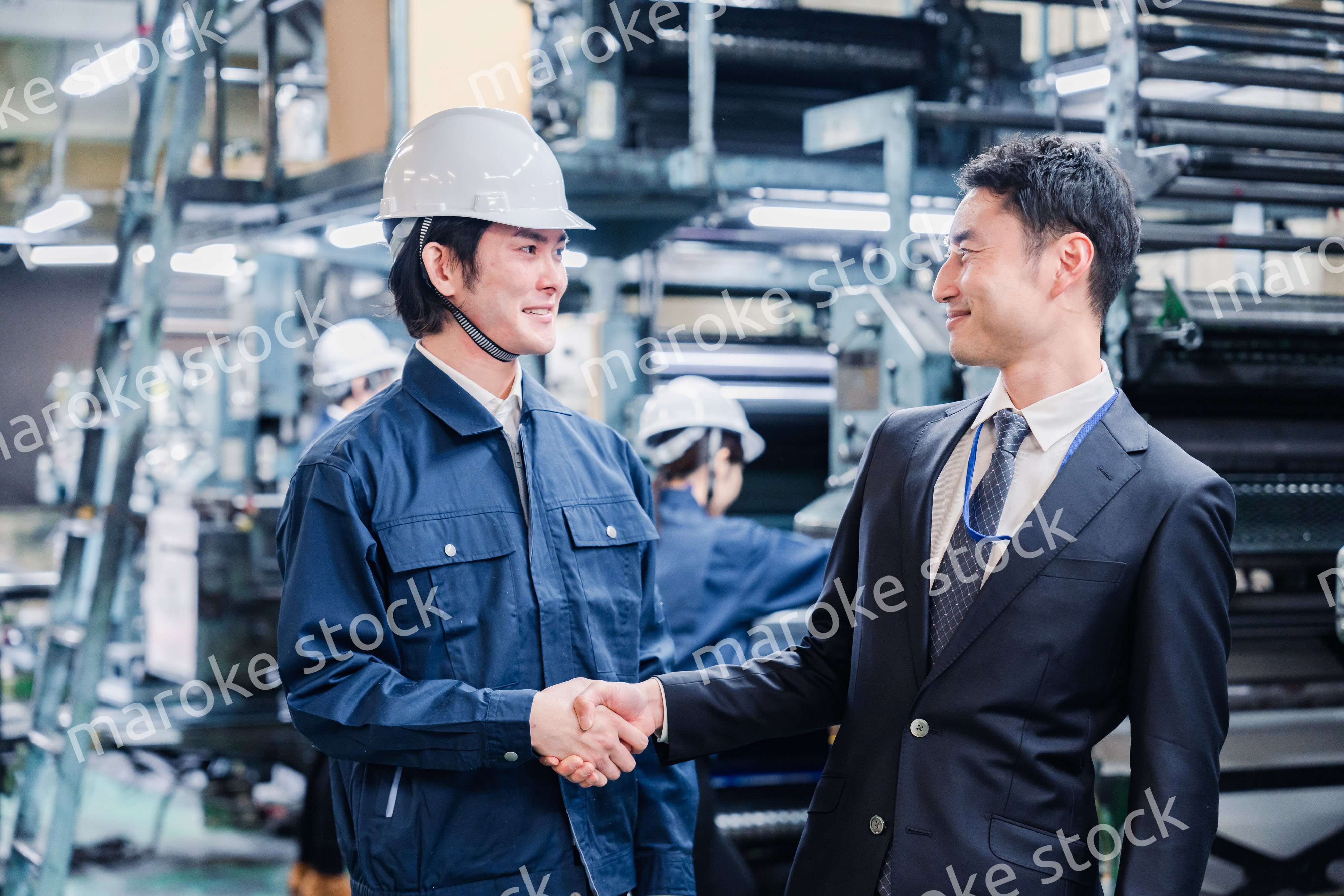 工場で握手をするビジネスマン