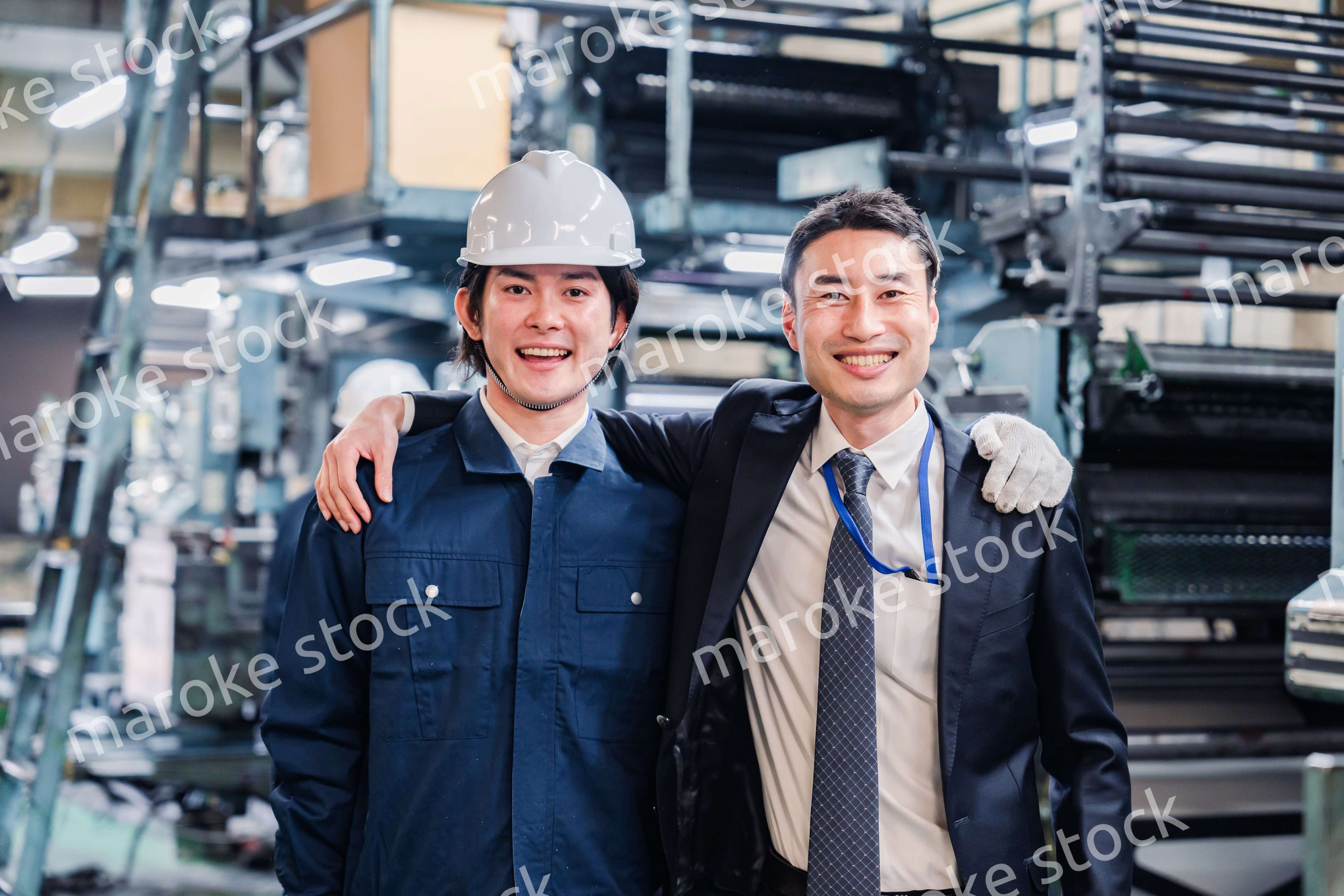 工場で肩を組む労働者と経営者