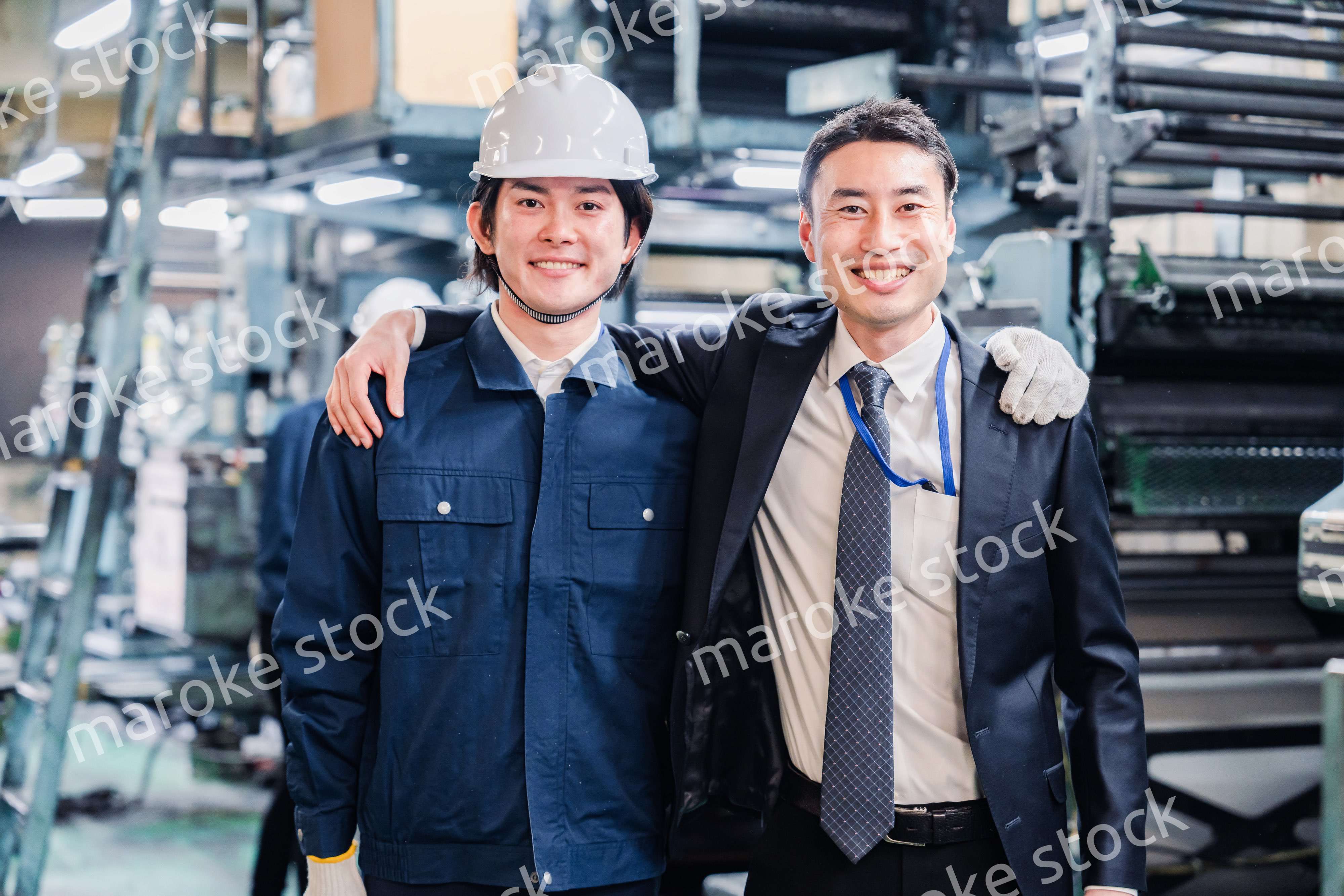 工場で肩を組む労働者と経営者