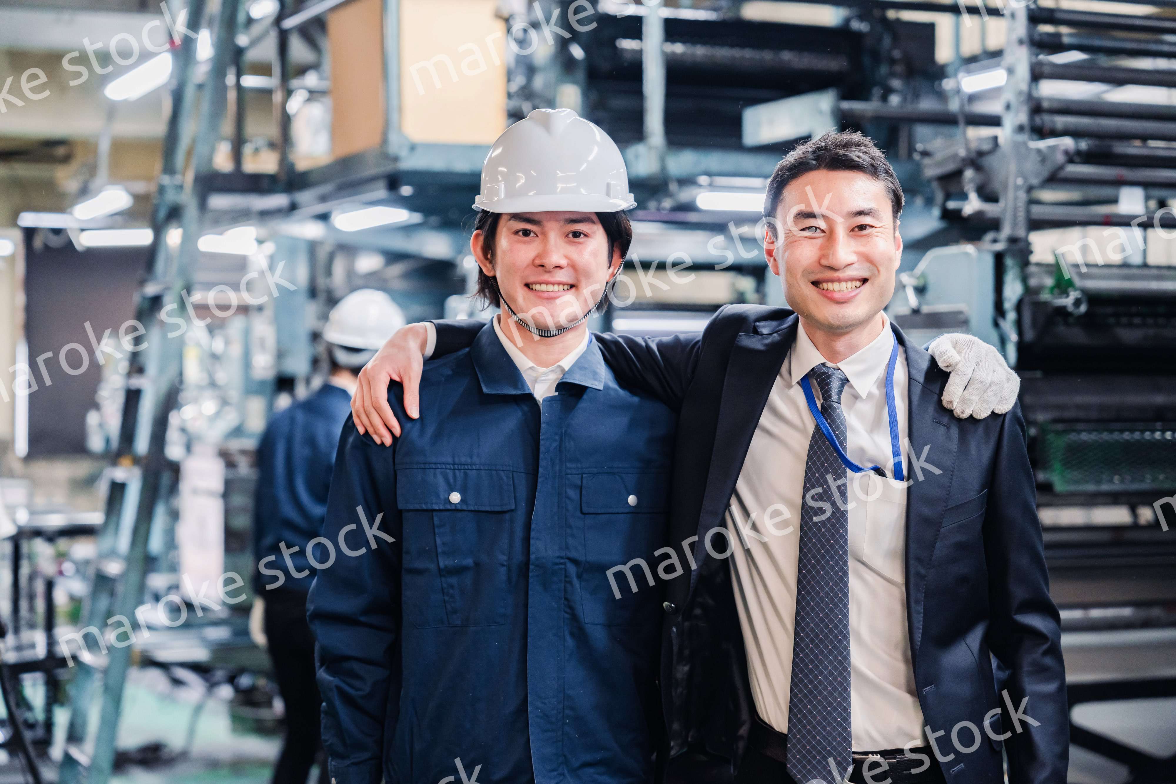 工場で肩を組む労働者と経営者