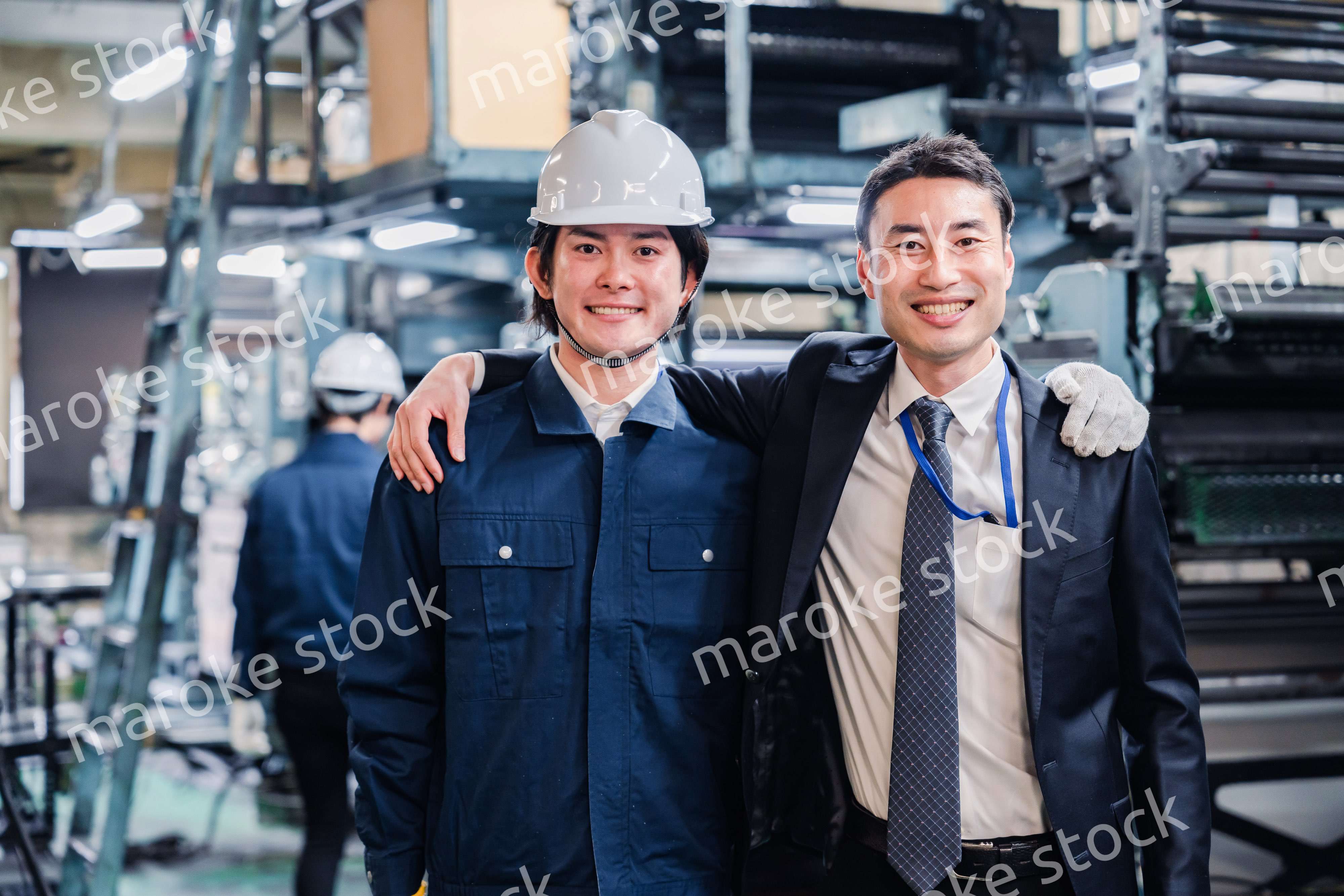 工場で肩を組む労働者と経営者